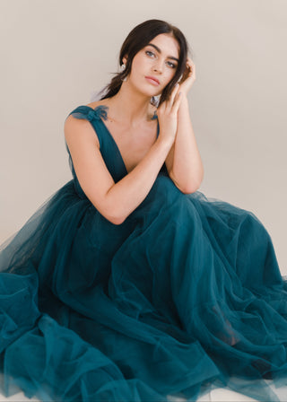 Woman wearing a long emerald dawn green bridesmaid dress with v neck and full skirt in tulle.