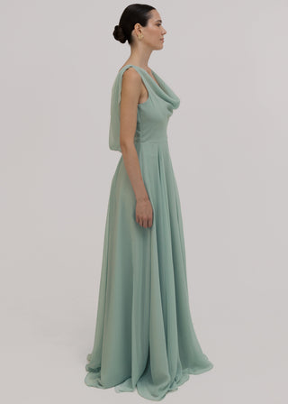 Woman wearing a light green bridesmaid dress with cowl neck and low back detail against a plain background by TH&TH Bridesmaids.