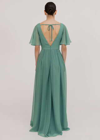 Model wears a sage green bridesmaid dress in chiffon with low v back details, flutter sleeves and flowing chiffon skirt by TH&TH Bridesmaids.