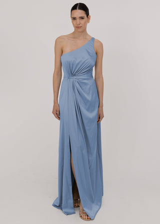 Model wearing a floor length dusty blue satin bridesmaid dress with one shoulder and slit in skirt by TH&TH Bridesmaids.
