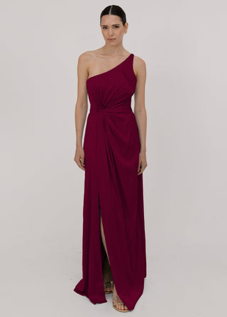 Model wearing a floor length burgundy satin bridesmaid dress with one shoulder and slit in skirt by TH&TH Bridesmaids.