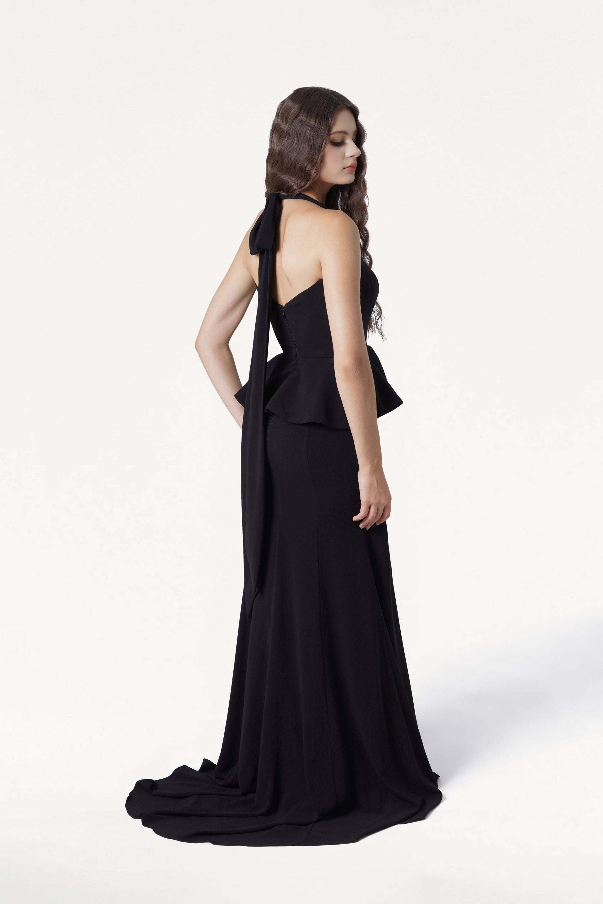Woman wearing a black evening gown with a flowing train on a white background