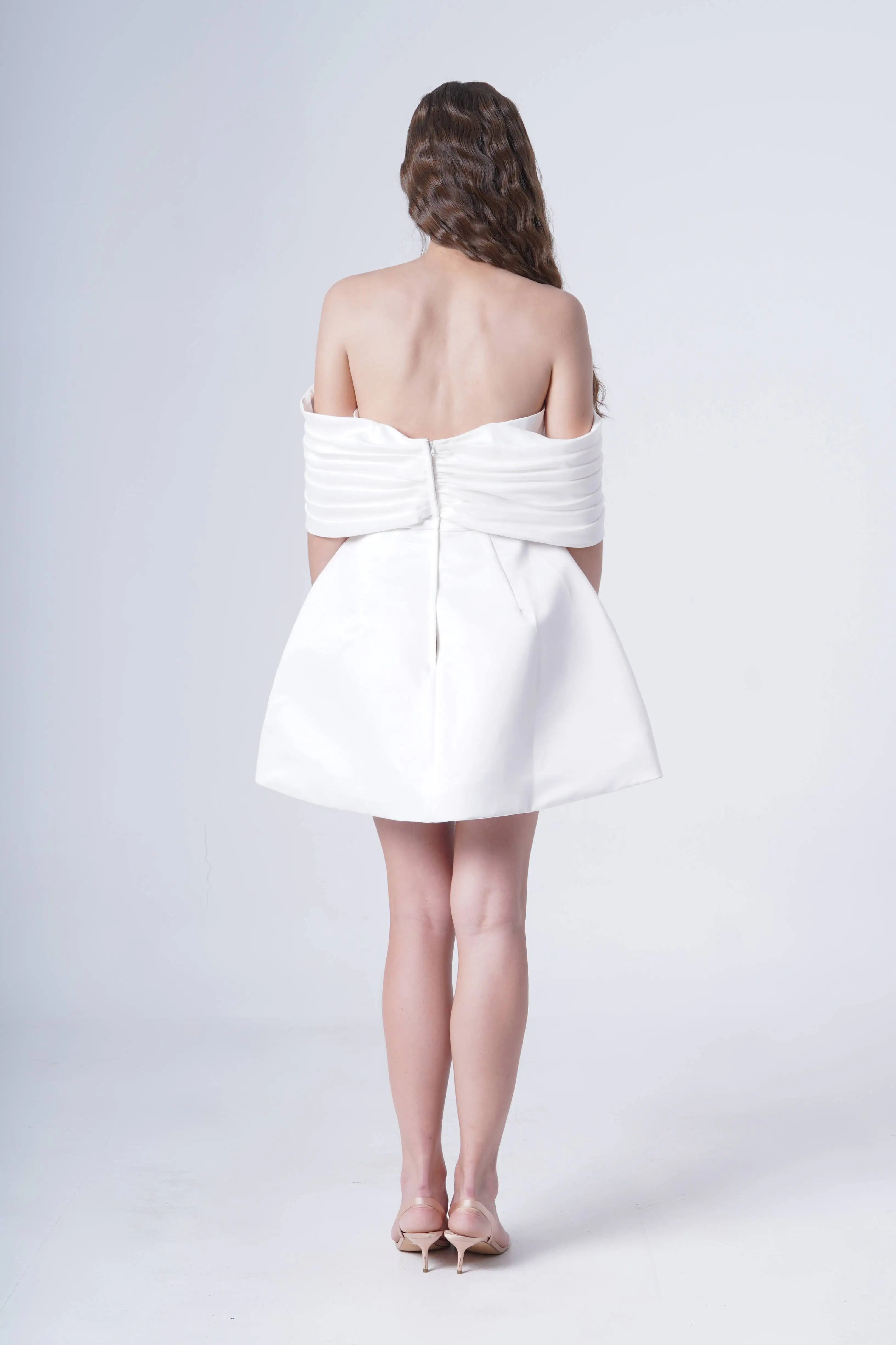 A woman wearing a strapless white dress back view on a white background.