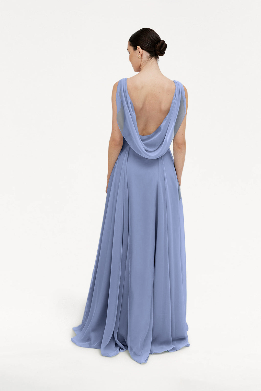 A woman in the TH&TH Athena Bridesmaid Dress in French Blue Chiffon, a floor-length sleeveless gown with a draped cowl back, stands facing away with dark hair in a sleek low bun against a plain white background.