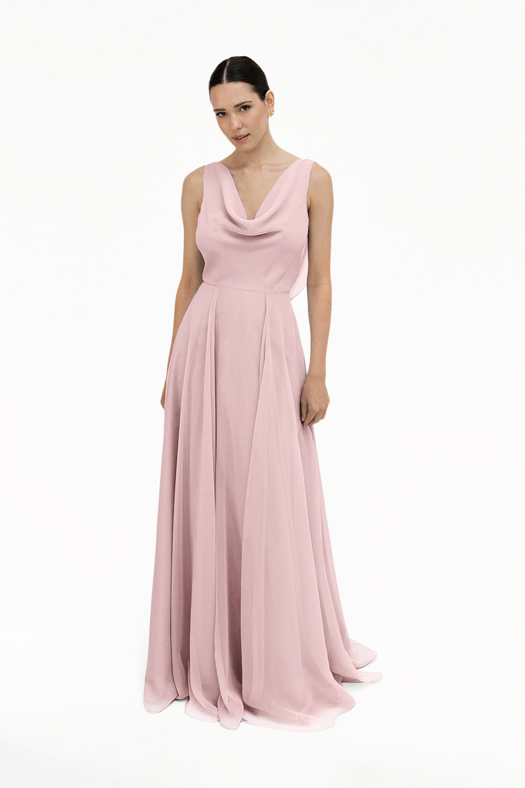 A woman faces forward against a white background, wearing the TH&TH Athena Bridesmaid Dress in smoked blush chiffon, featuring a floor-length, sleeveless design with a draped cowl neck and flowing skirt.