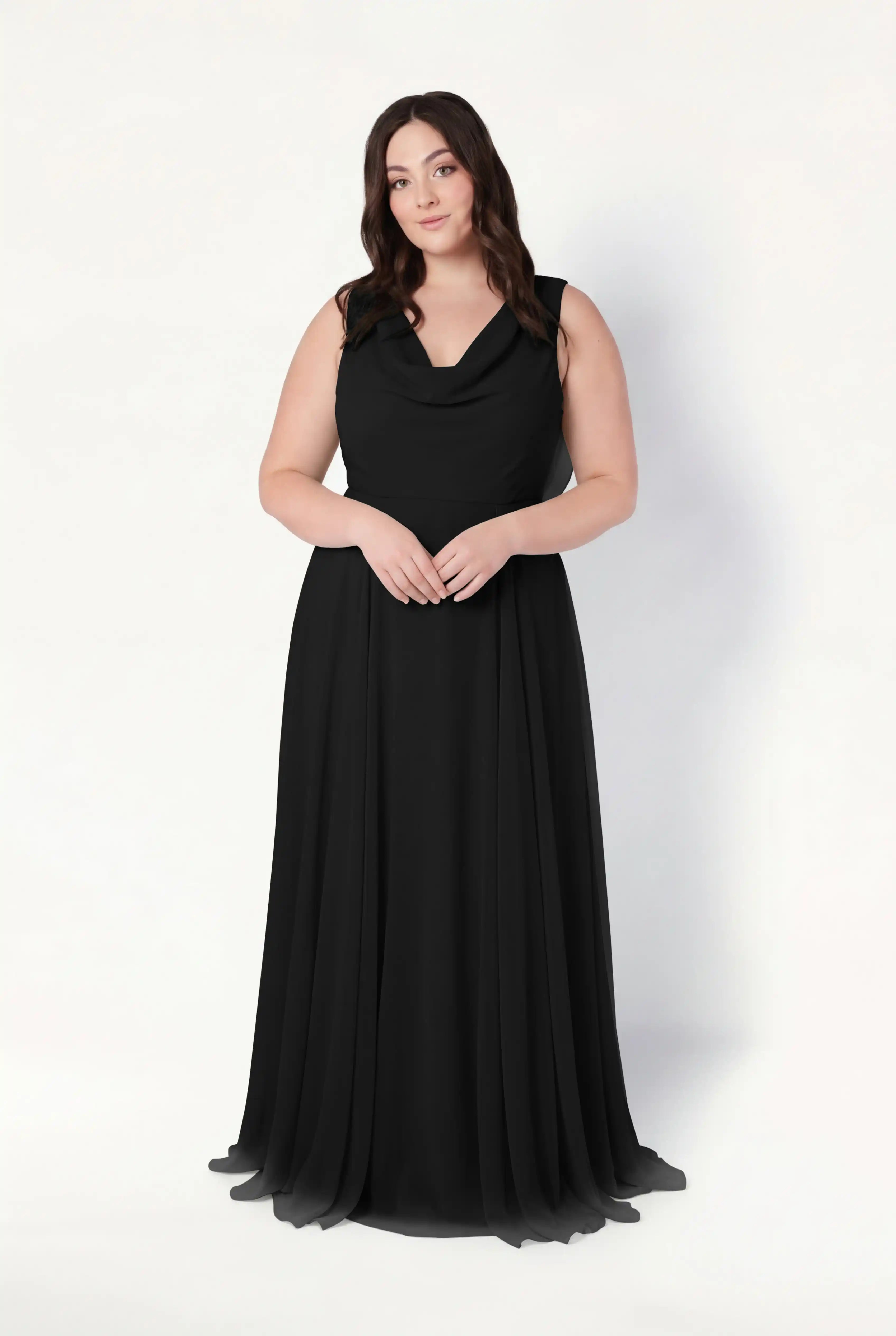A woman with long brown hair stands against a white background, wearing the TH&TH Athena Bridesmaid Dress in Black Chiffon—a sleeveless, floor-length gown with a cowl neck and flowing fabric, perfect as a modern bridesmaid dress.