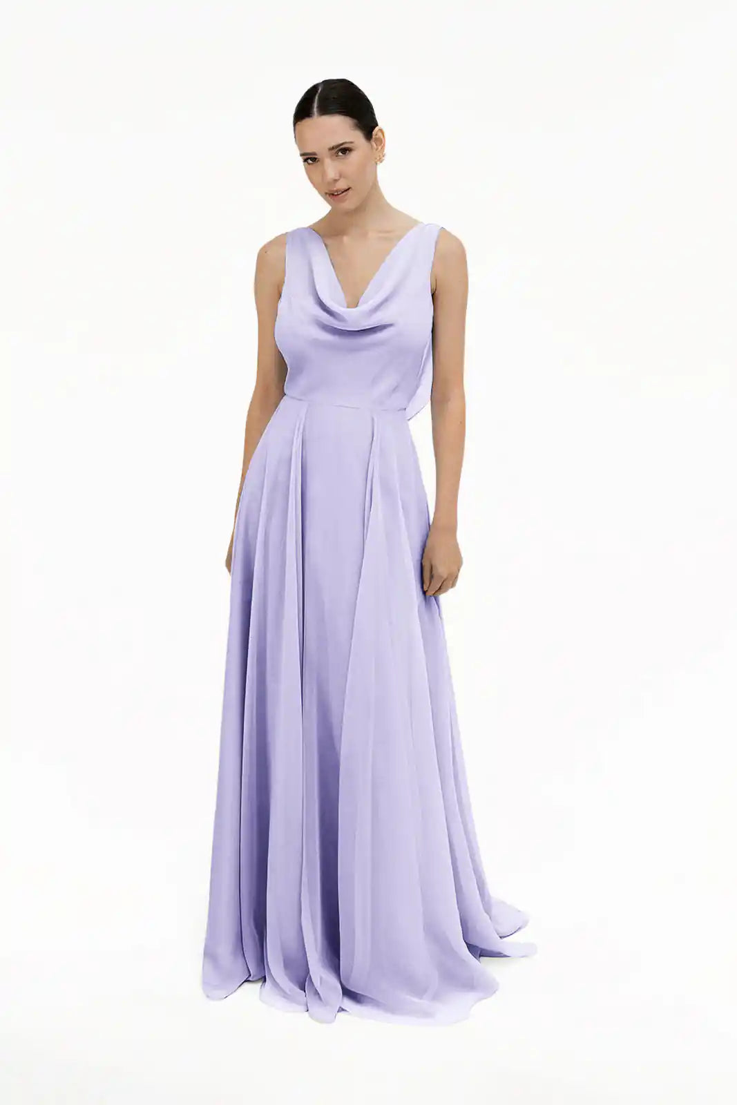 A woman stands against a white background wearing the TH&TH Athena Bridesmaid Dress in Lilac Mist chiffon, featuring a sleeveless design, draped cowl neckline, and a flowing floor-length skirt.