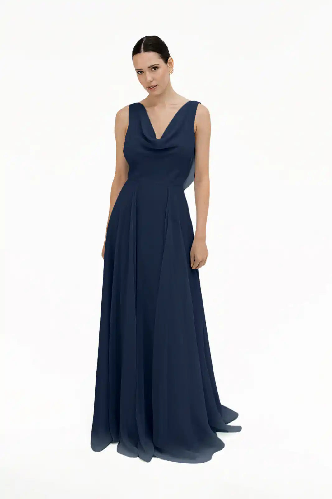 A woman stands against a white background wearing the TH&TH Athena Bridesmaid Dress in navy chiffon, featuring a sleeveless design, cowl neck, and flowing floor-length skirt.