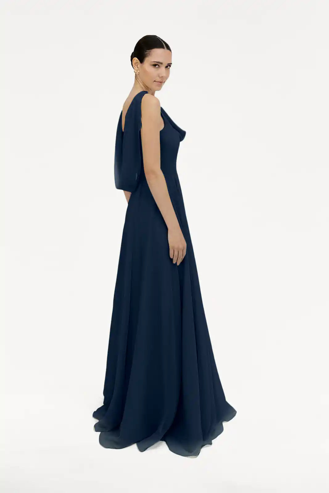 A woman models the TH&TH Athena Bridesmaid Dress in navy chiffon—a sleeveless, floor-length gown—standing against a plain white background with her hair pulled back, glancing over her shoulder.