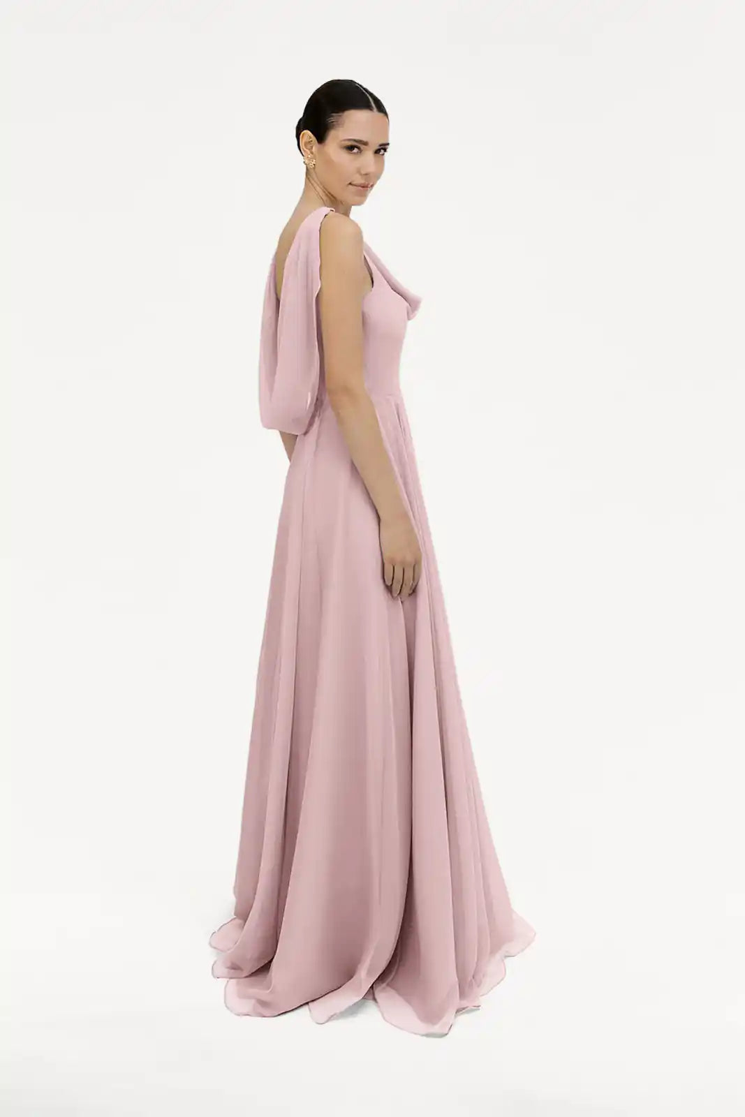 A woman poses in profile against a plain white background, wearing the TH&TH Athena Bridesmaid Dress in smoked blush chiffon—a floor-length gown with draped sleeves.