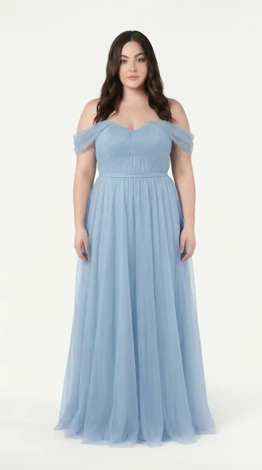 A woman with long brown hair wears the TH&TH Bardot Bridesmaid Dress in Dusty Blue Tulle, a floor-length off-shoulder gown, as she stands facing forward against a plain white background.