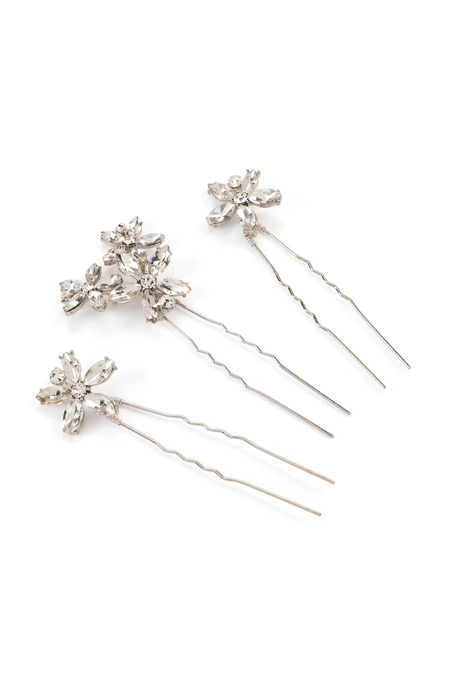 Four Beaumont Floral Hair Pins by TH&TH, each featuring clear faceted crystal floral tops and wavy stems, are arranged on a white background—elegant wedding hair accessories resembling flowers or starbursts.