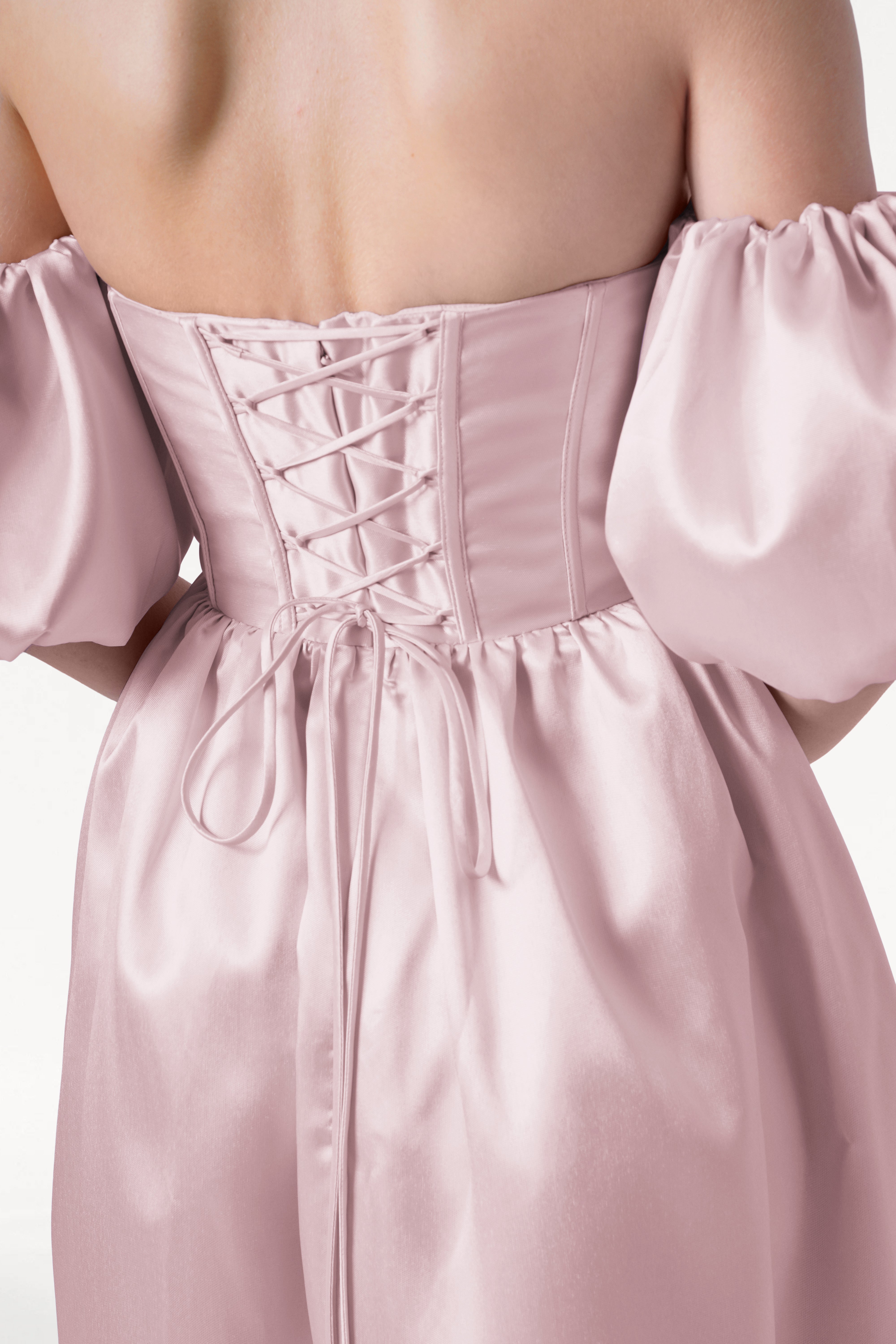 A close-up of a person wearing the TH&TH Blair Bridesmaid Dress in Blush Pink Satin Twill, featuring off-the-shoulder puff sleeves and a lace-up back—ideal for anyone seeking unique, elegant bridal party style.