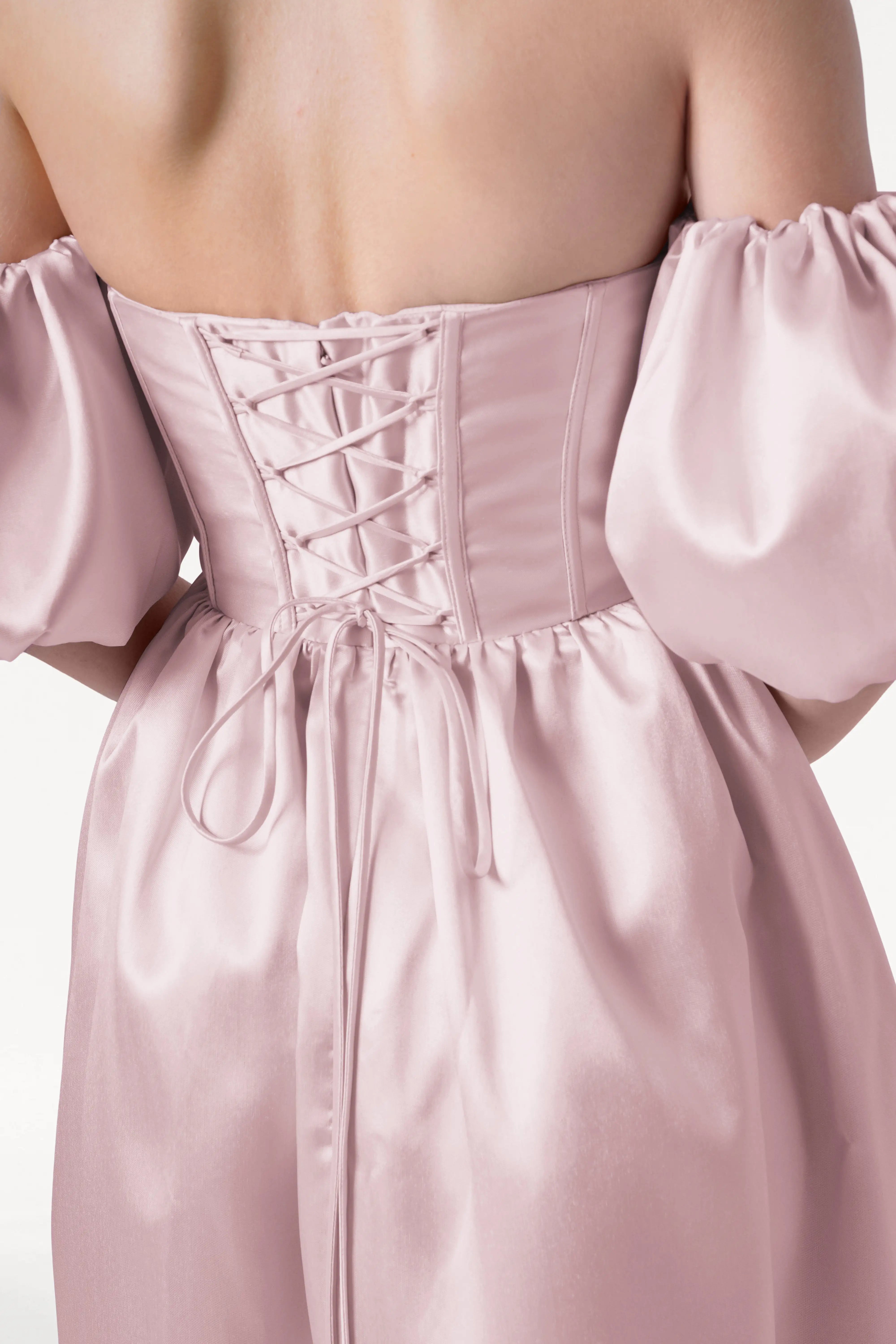 A close-up of a person wearing the TH&TH Blair Bridesmaid Dress in Blush Pink Satin Twill, featuring off-the-shoulder puff sleeves and a lace-up back—ideal for anyone seeking unique, elegant bridal party style.