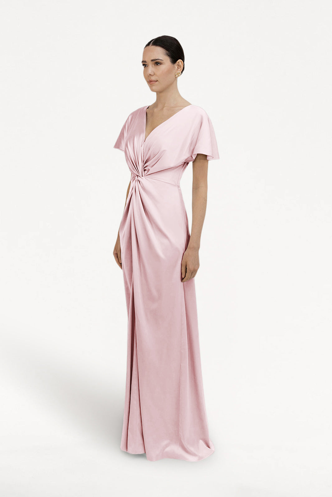 A woman wears the TH&TH Camilla Bridesmaid Dress in Blush Pink Satin, featuring flutter sleeves, a V-neckline, and a gathered twist waist, standing against a plain white background.