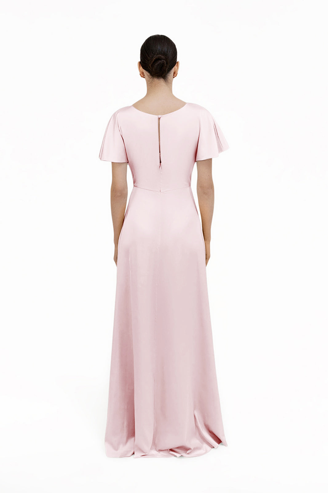 A person faces away, wearing the TH&TH Camilla Bridesmaid Dress in Blush Pink Satin—a floor-length gown with short flutter sleeves and a small keyhole at the upper back—set against a plain white background.