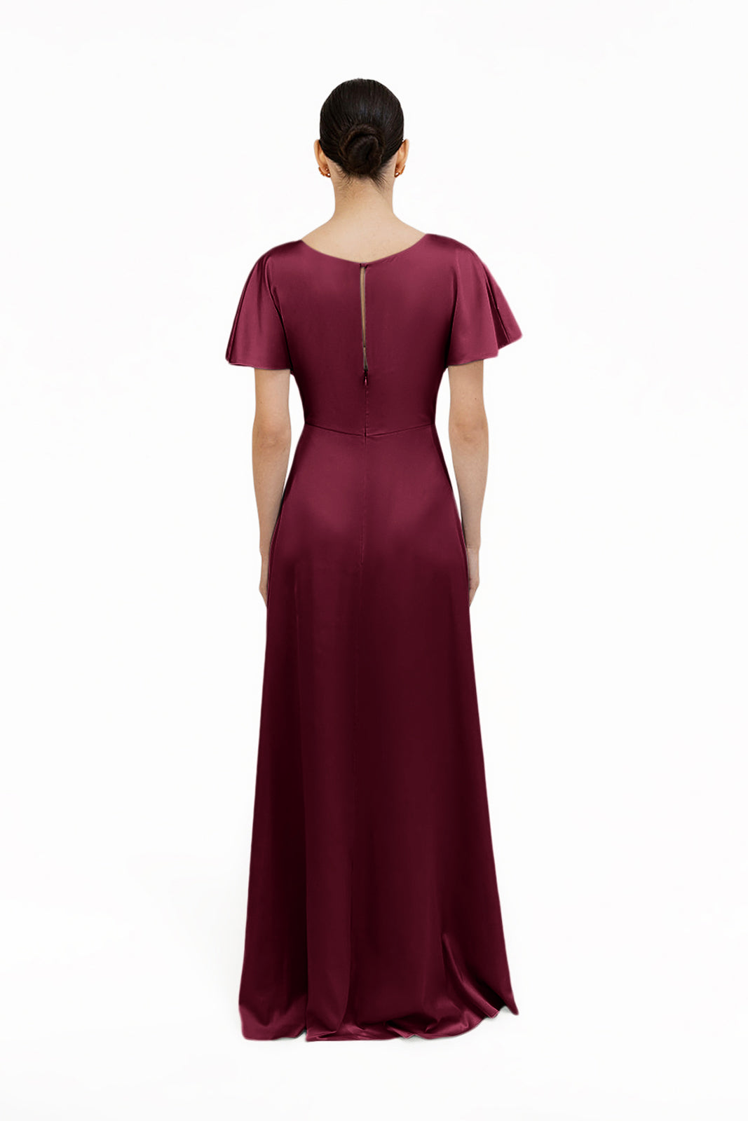 A woman faces away in the Camilla Bridesmaid Dress by TH&TH—a floor-length, short-sleeved merlot satin gown with a fitted waist and keyhole upper back—set against a plain white background.