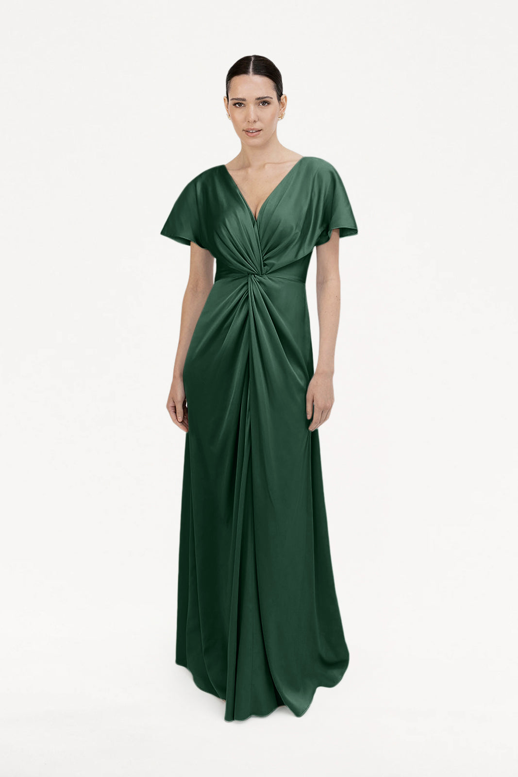 A woman stands facing forward against a plain white background, wearing the TH&TH Camilla Bridesmaid Dress in Olive Grove Satin—a floor-length gown with short sleeves, a deep V-neckline, and gathered draping at the waist.