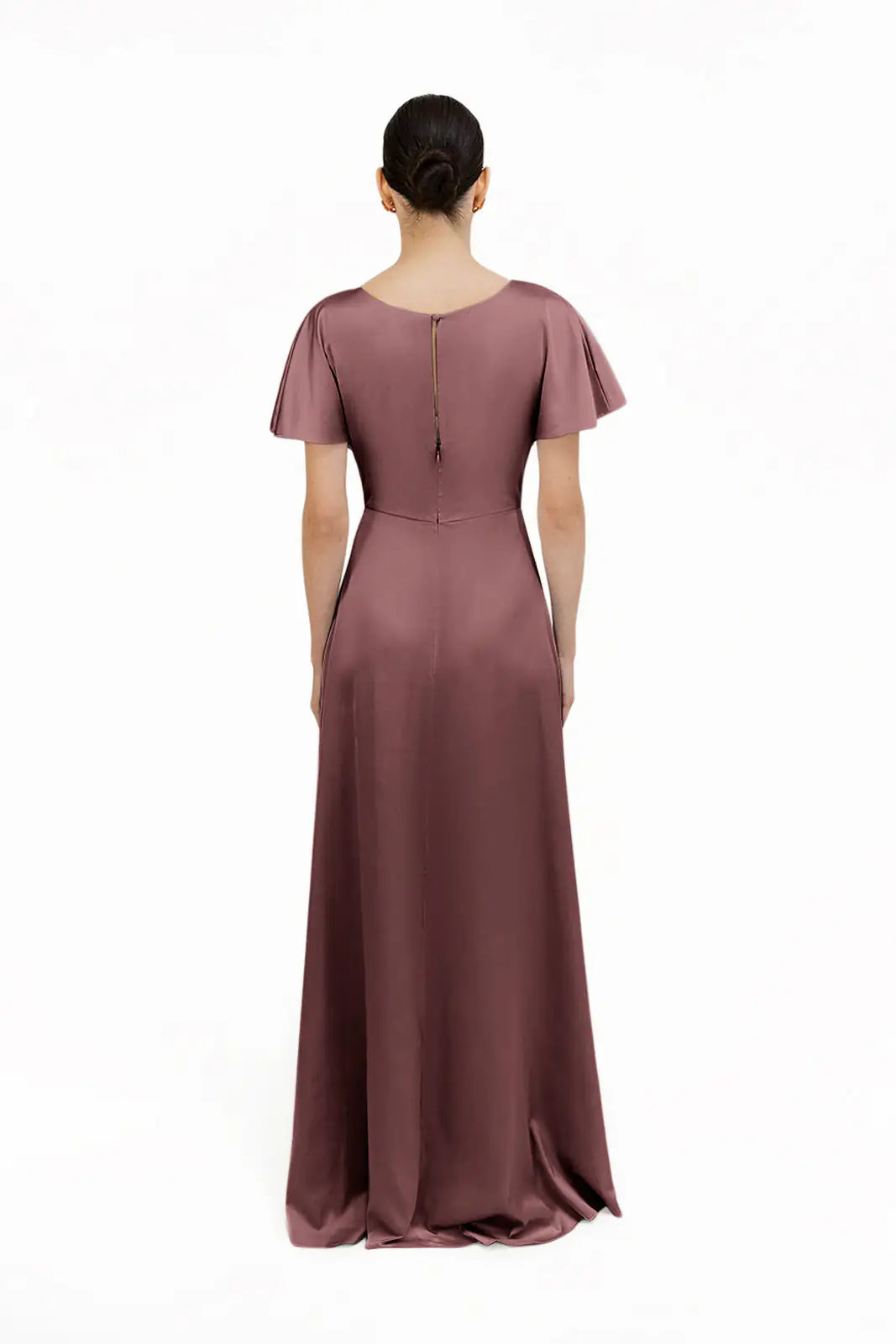A woman with dark hair in a low bun is shown from the back, wearing the TH&TH Camilla Bridesmaid Dress—a floor-length, short-sleeved gown in chocolate brown satin with a zipper down the upper back—against a plain white background.