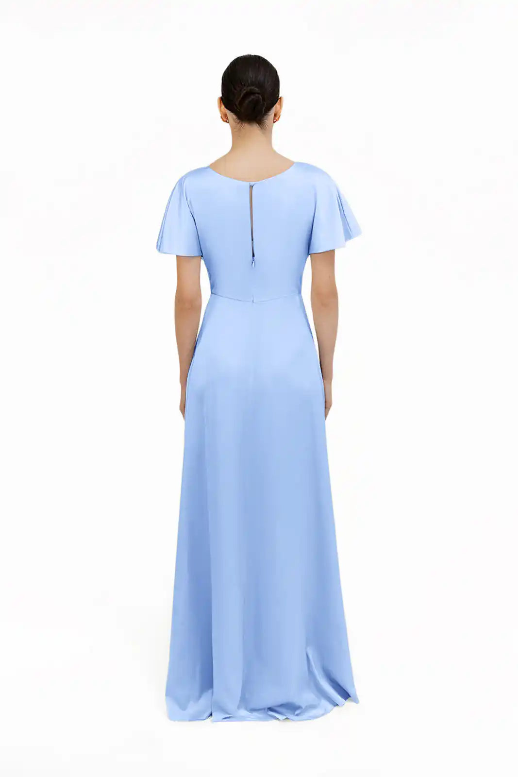 A woman faces away in the TH&TH Camilla Bridesmaid Dress, a floor-length gown in dusty blue satin with short flutter sleeves and a back zipper, set against a plain white background.