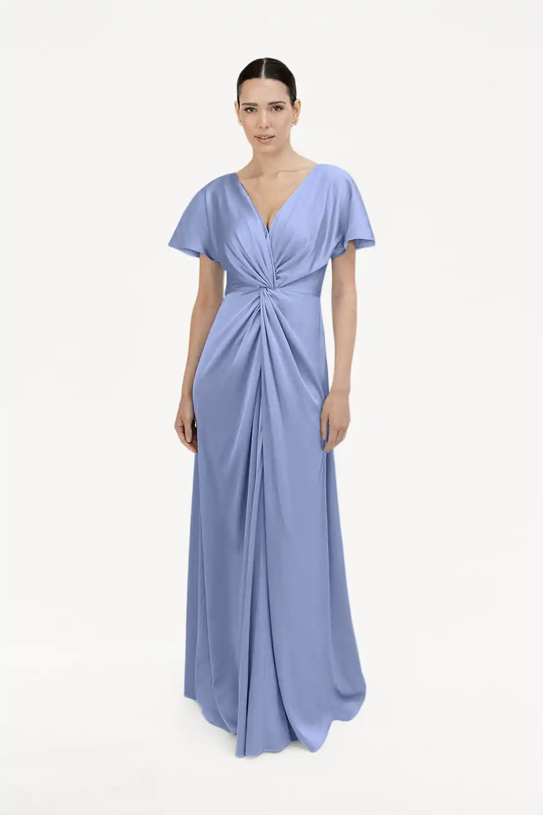 A woman poses against a white backdrop in the Camilla Bridesmaid Dress in French Blue Satin by TH&TH, a size-inclusive, floor-length gown with short sleeves, a twist-knot front bodice, and a flattering V-neckline.