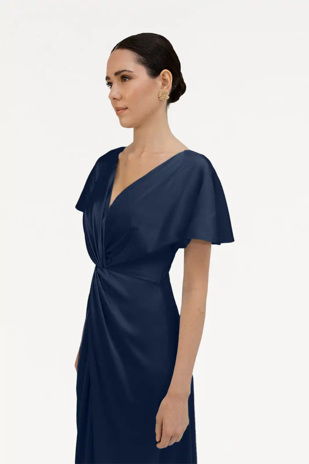 A woman with dark hair in a low bun wears the TH&TH Camilla Bridesmaid Dress in Navy Satin, a short-sleeved V-neck style featuring a twist-knot bodice, against a plain white background.
