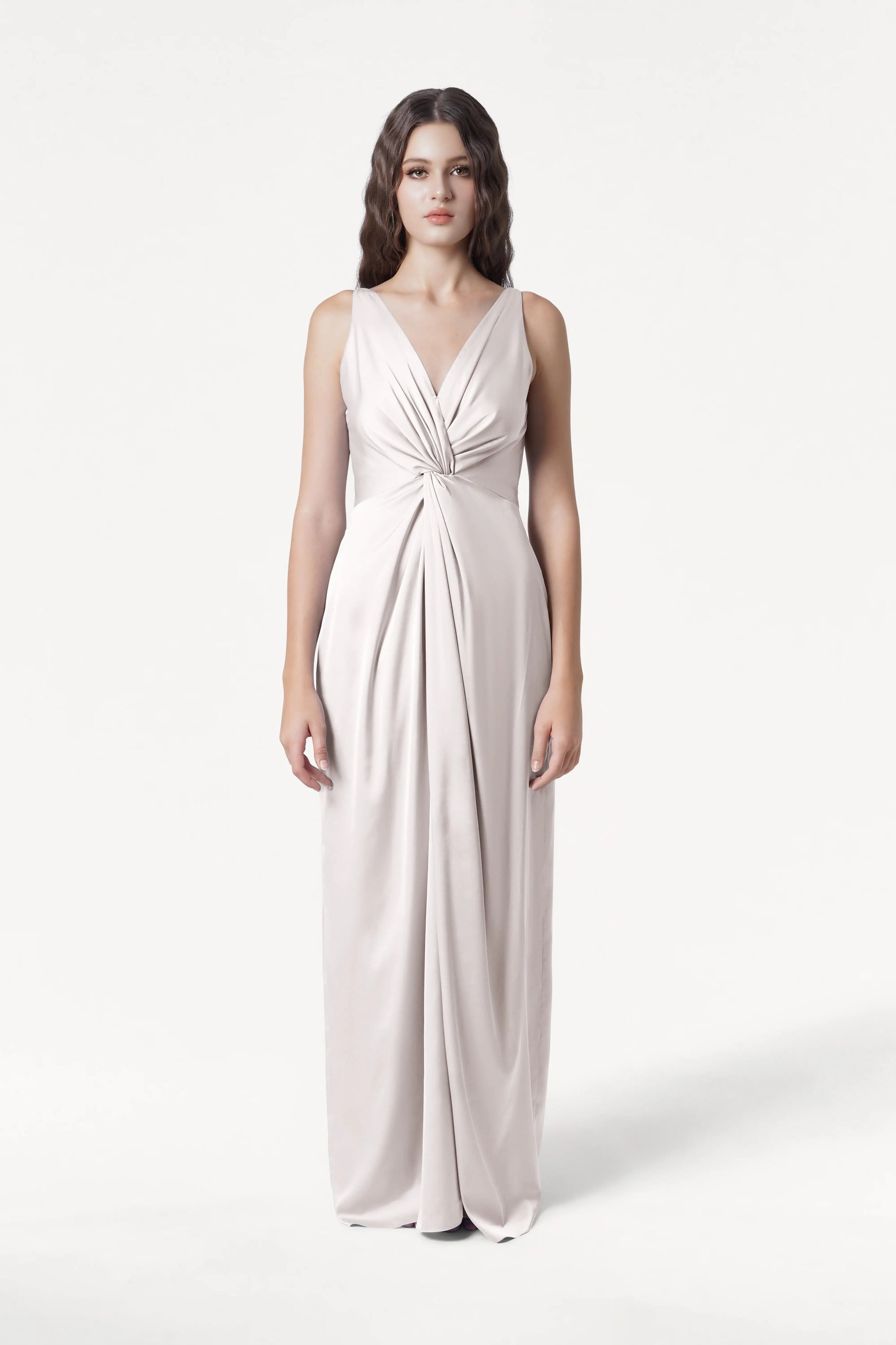 A woman faces forward in the TH&TH Carmen Bridesmaid Dress in Oyster Satin, featuring a sleek satin finish, deep V-neckline, twist-knot front, and gathered waist—an elegant choice for modern bridal parties, set on a plain white background.
