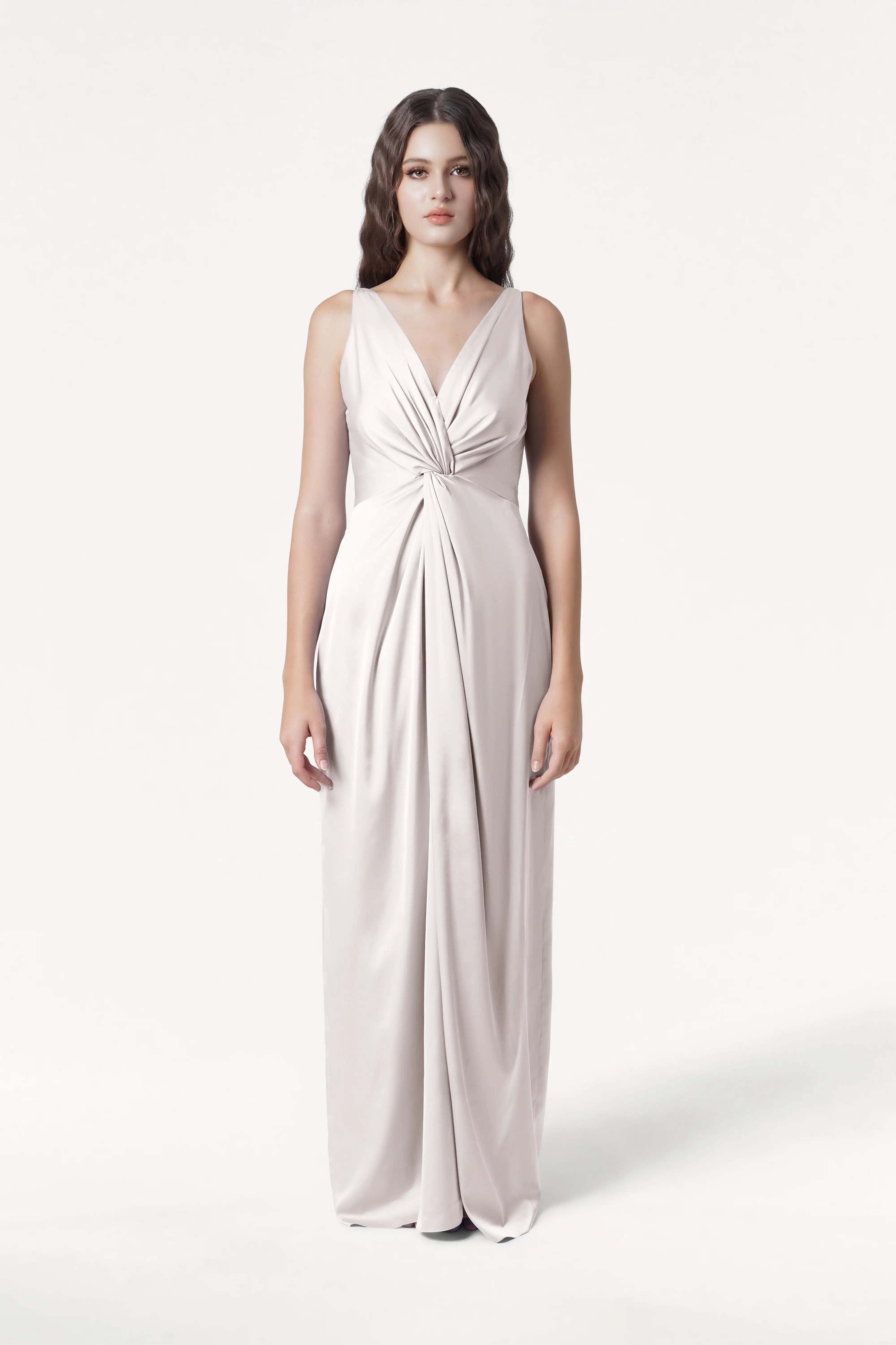 A woman faces forward in the TH&TH Carmen Bridesmaid Dress in Oyster Satin, featuring a sleek satin finish, deep V-neckline, twist-knot front, and gathered waist—an elegant choice for modern bridal parties, set on a plain white background.