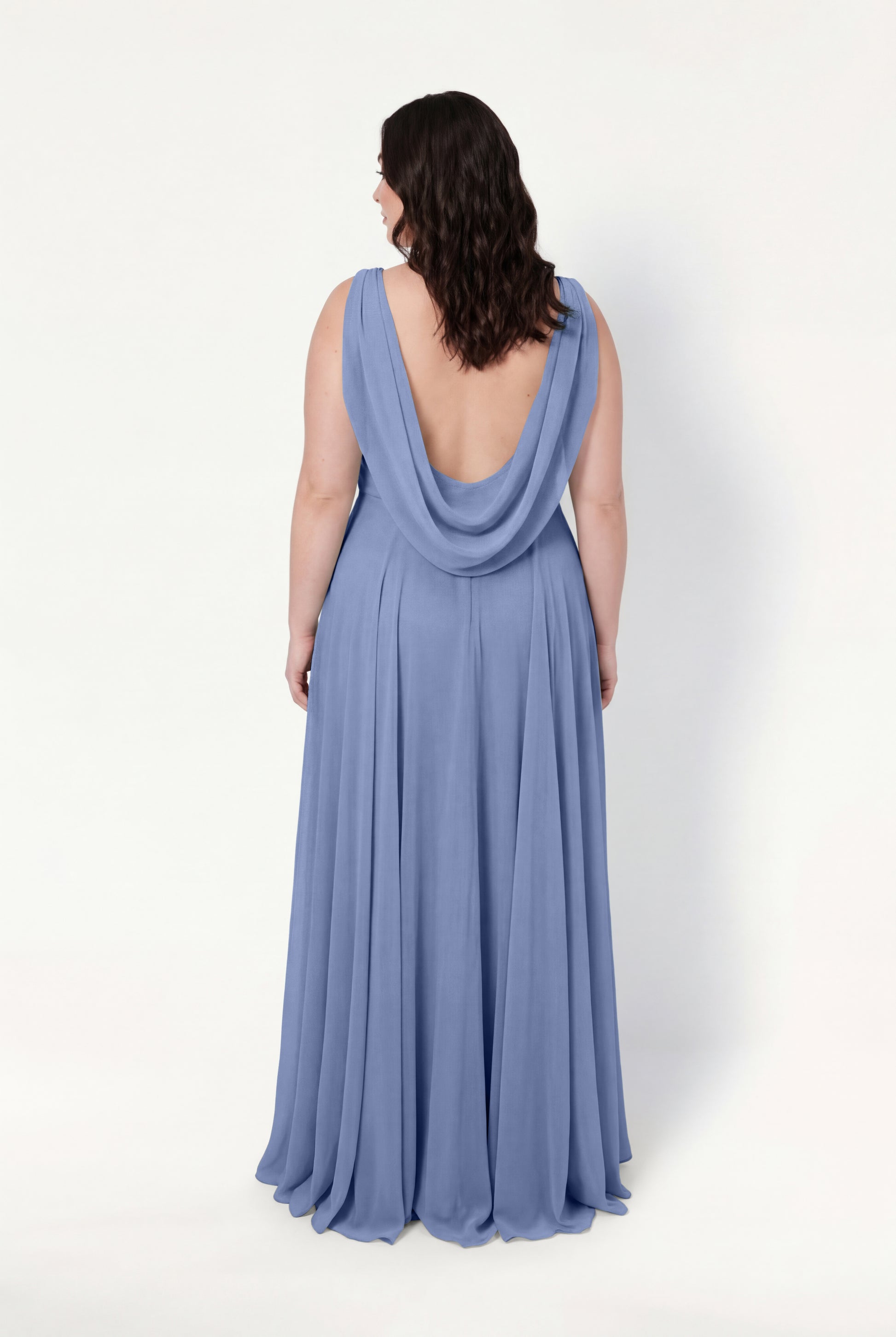 A woman with wavy brown hair faces away, showcasing the TH&TH Athena Bridesmaid Dress in French Blue Chiffon. The sleeveless gown features a draped cowl and open back, elegantly set against a plain white background.