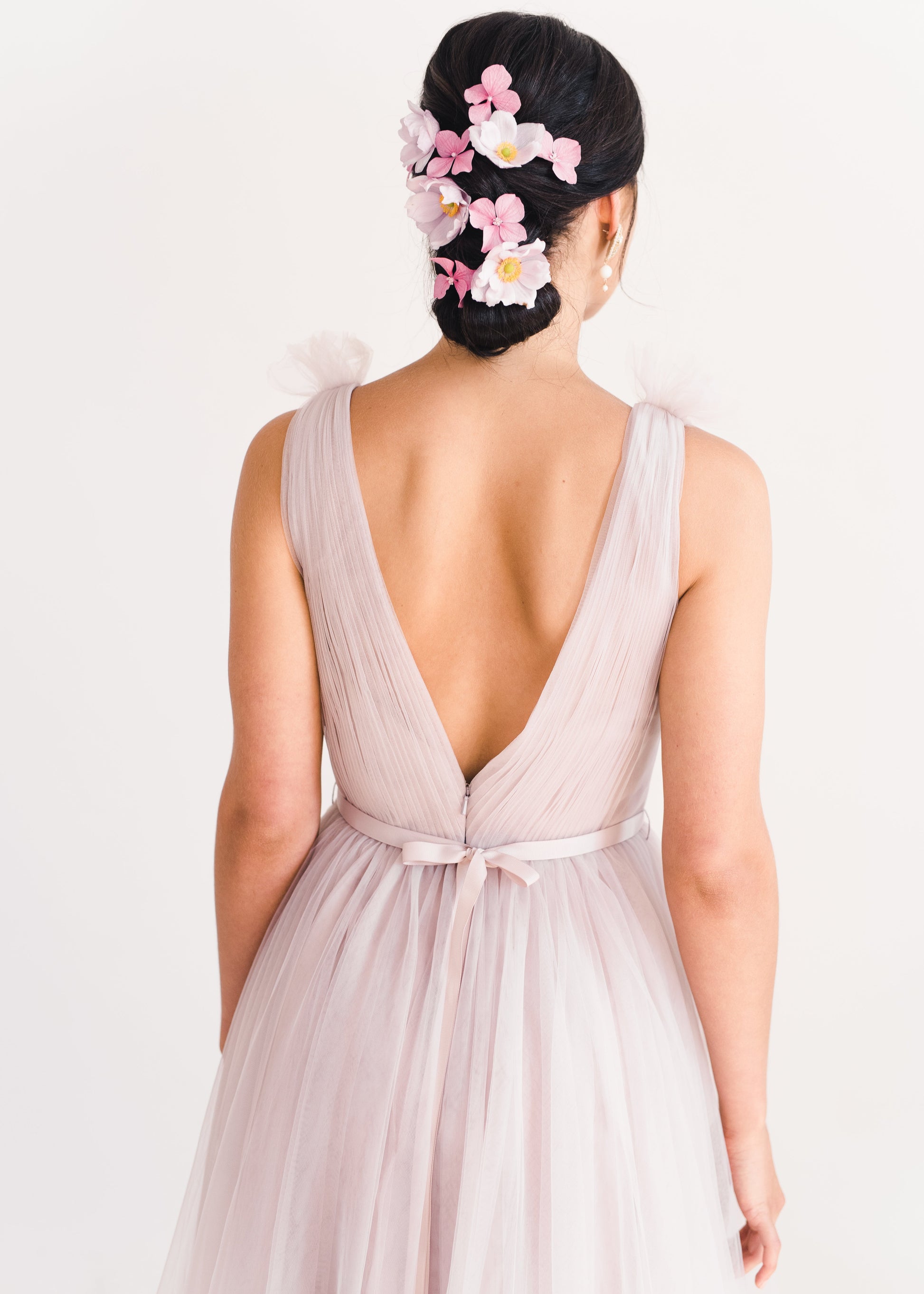 Woman wearing a long smoked blush pink bridesmaid dress with V neck and full skirt in tulle