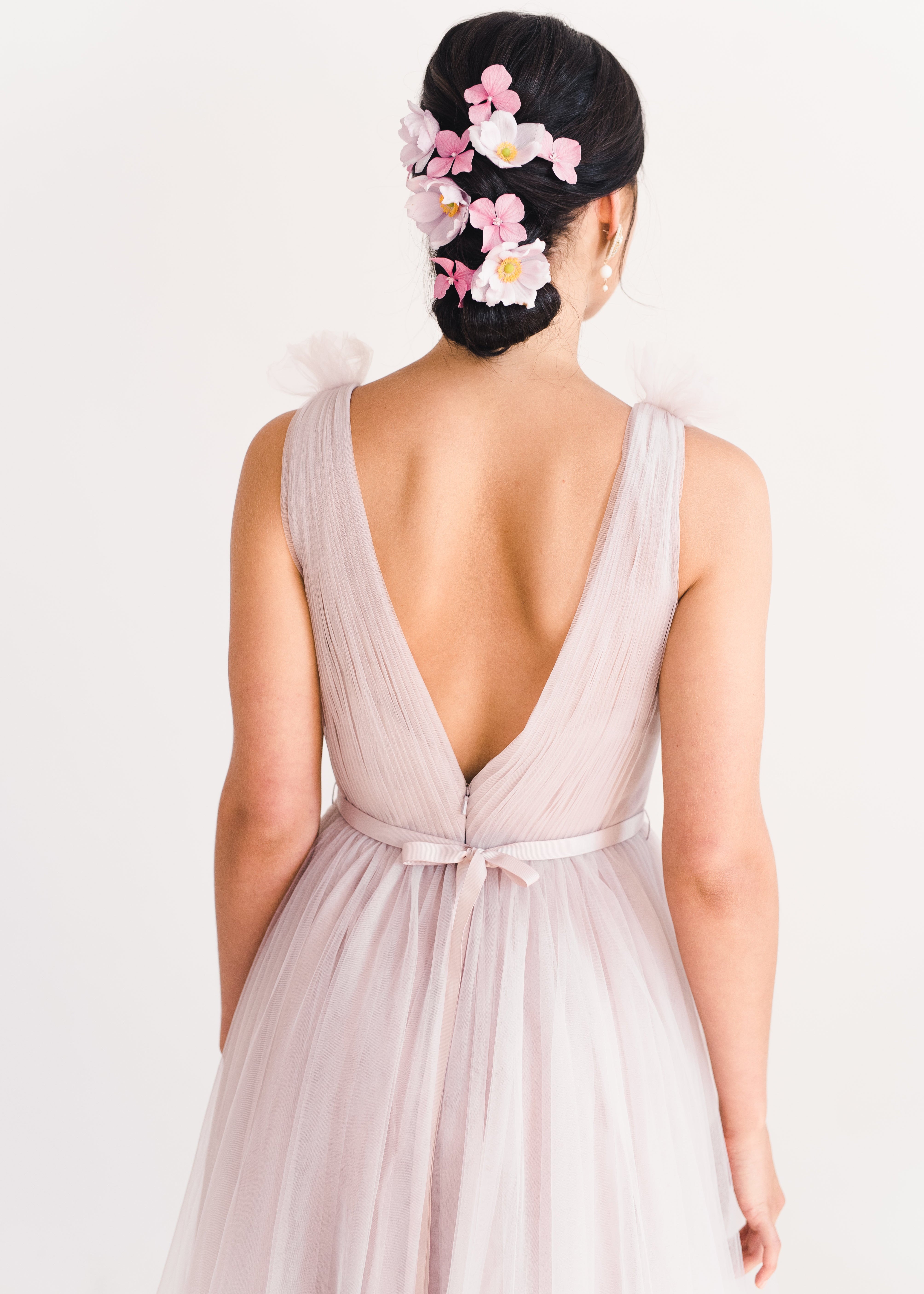 Woman wearing a long smoked blush pink bridesmaid dress with V neck and full skirt in tulle