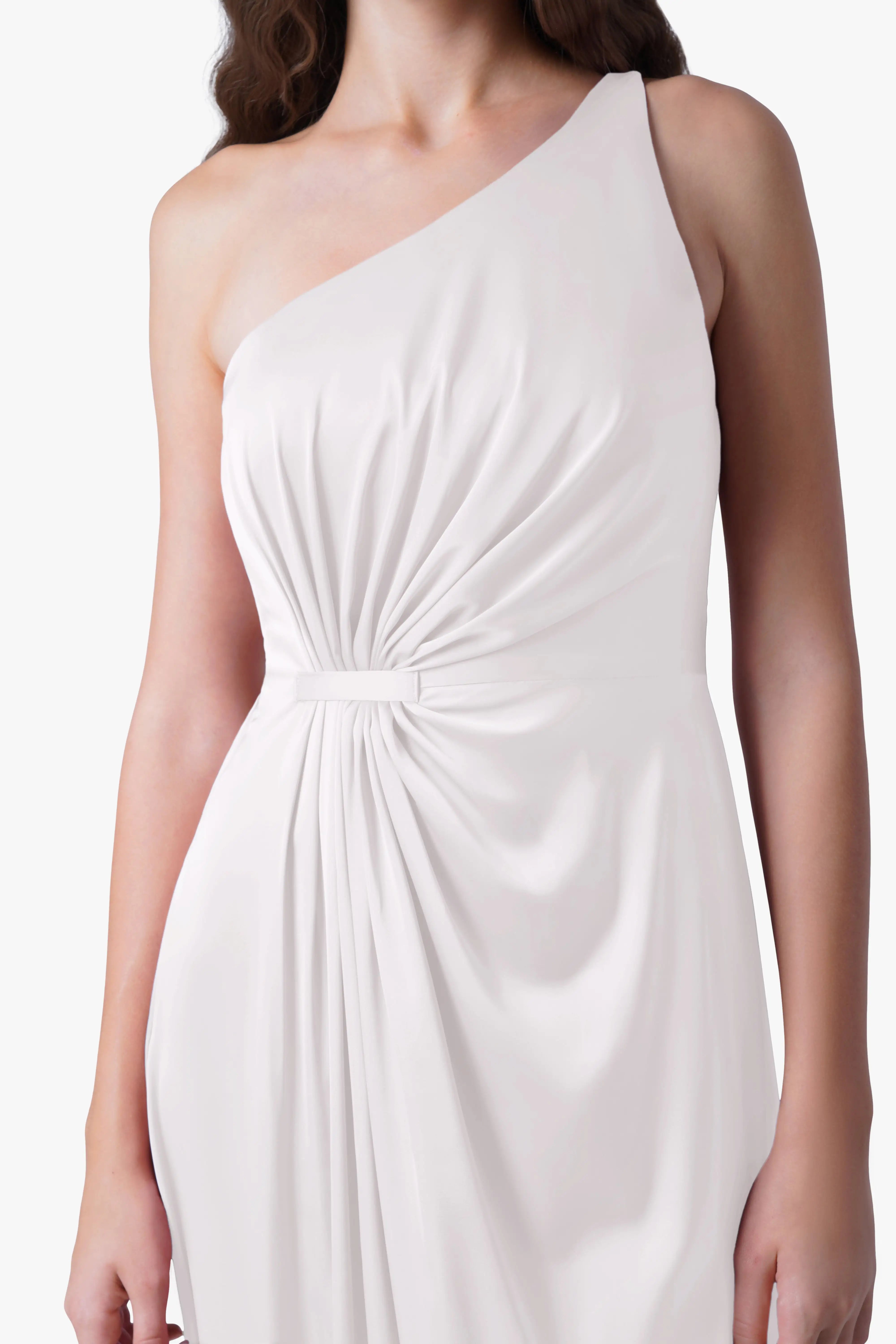 A woman models the TH&TH Greta Dress in Ivory Satin— a sleeveless, one-shoulder gown with Grecian-inspired ruched waist— standing against a plain white background. Her face is not shown.