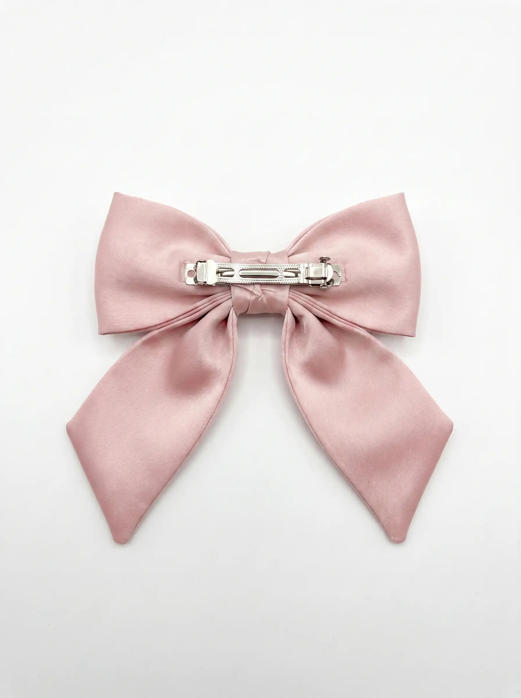 Pink satin bow hair clip on a light gray background