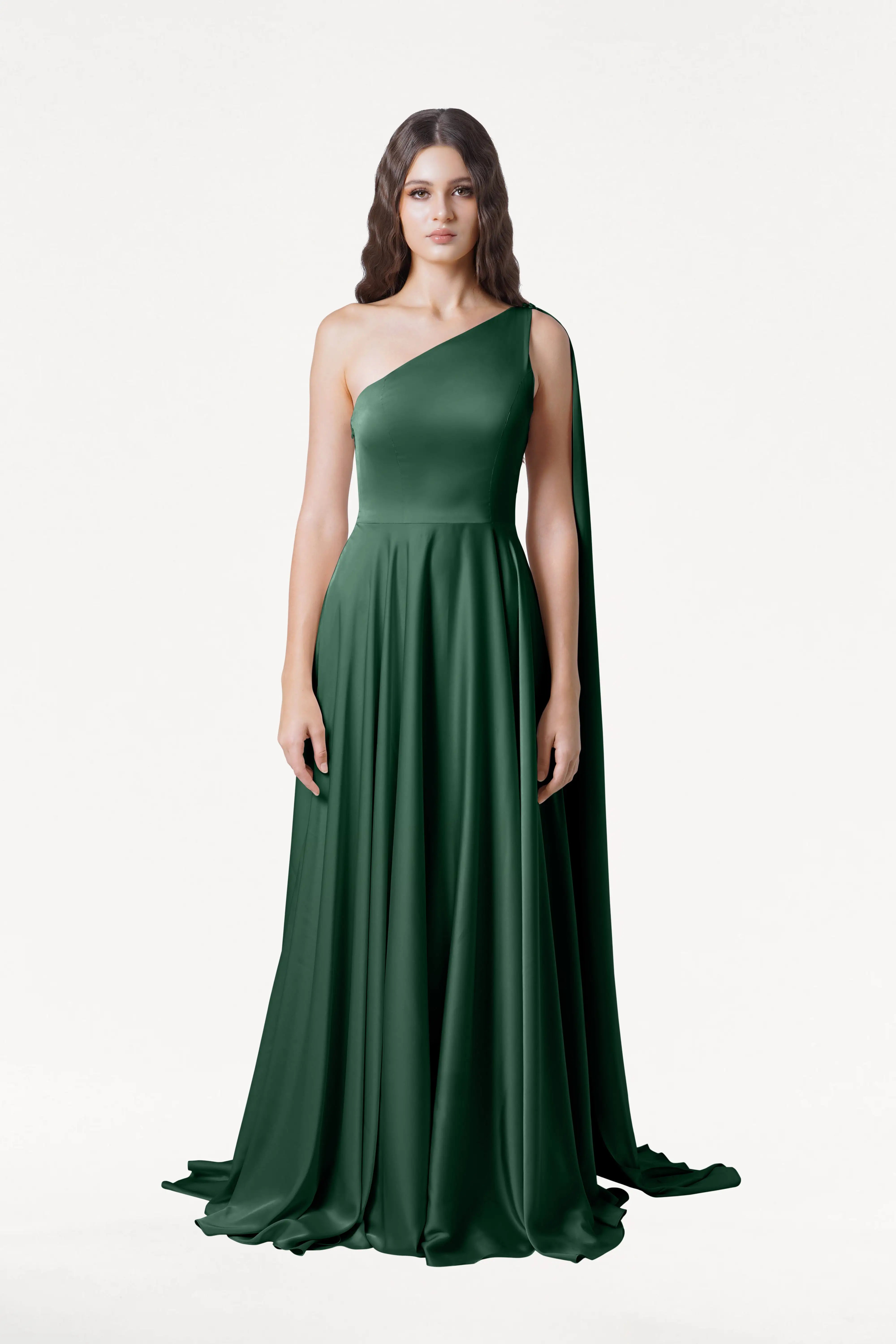 A woman faces forward in the TH&TH Lyra Bridesmaid Dress in Olive Grove Satin, a size-inclusive, floor-length one-shoulder gown with a long draped cape. She has long wavy brown hair and a neutral expression against a white background.