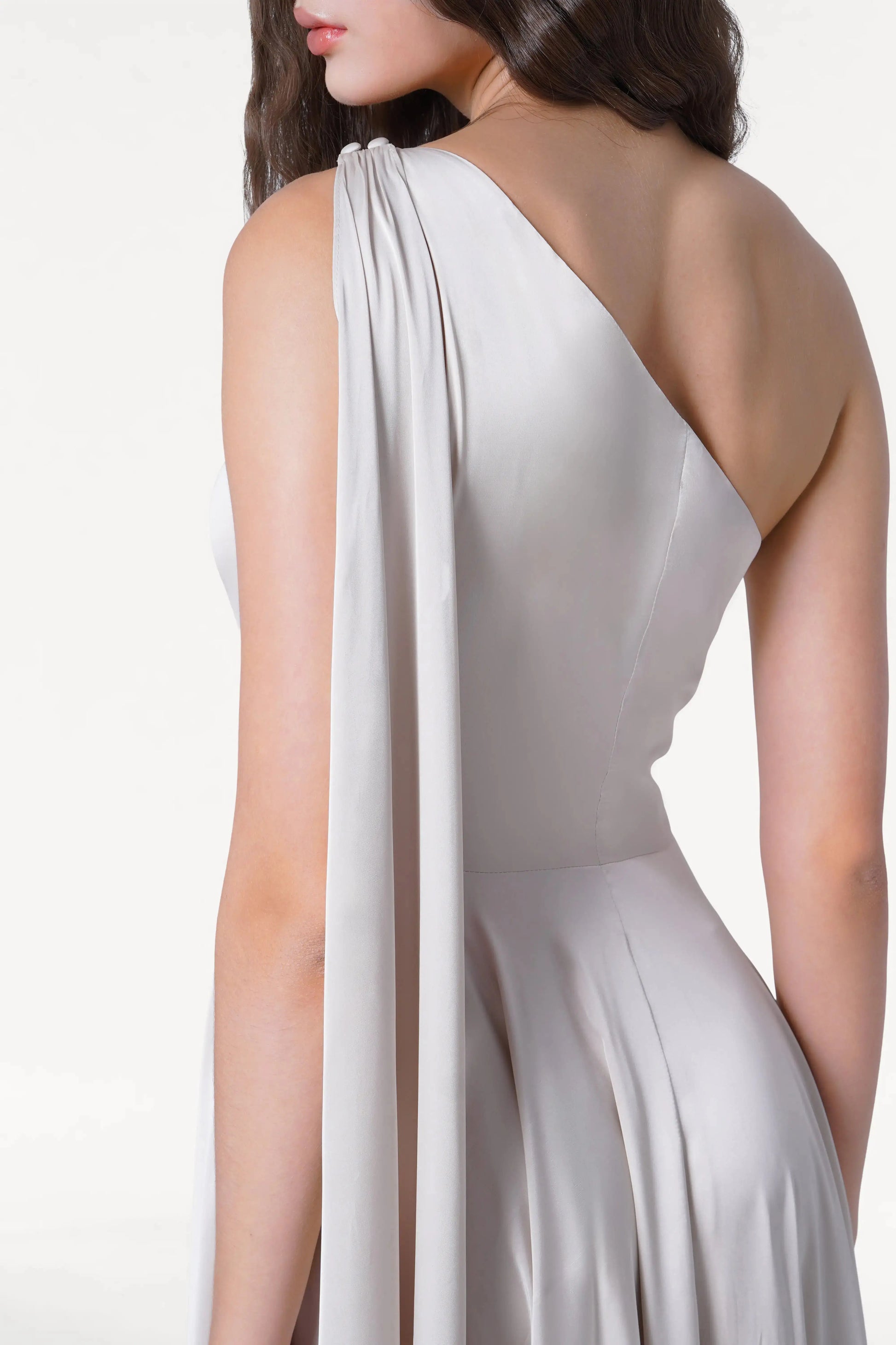 A woman models the TH&TH Lyra Bridesmaid Dress in Oyster Satin, a size-inclusive, one-shoulder gown with draped detail, shown from the back and side against a plain white background.