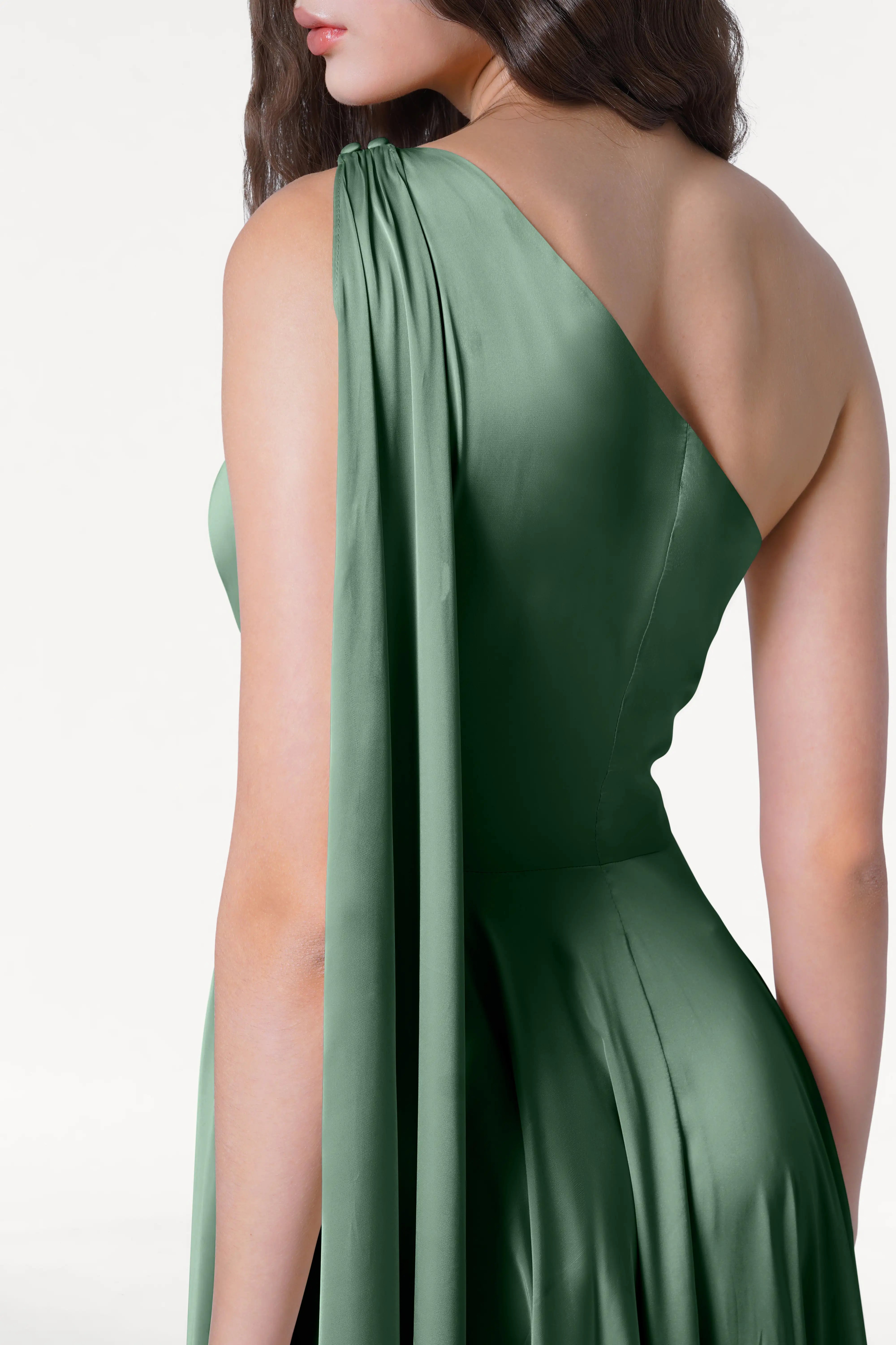 A woman wearing the TH&TH Lyra Bridesmaid Dress in Sage Green Satin, a size-inclusive one-shoulder gown with draped, flowing shoulder detail, shown from the back and side.