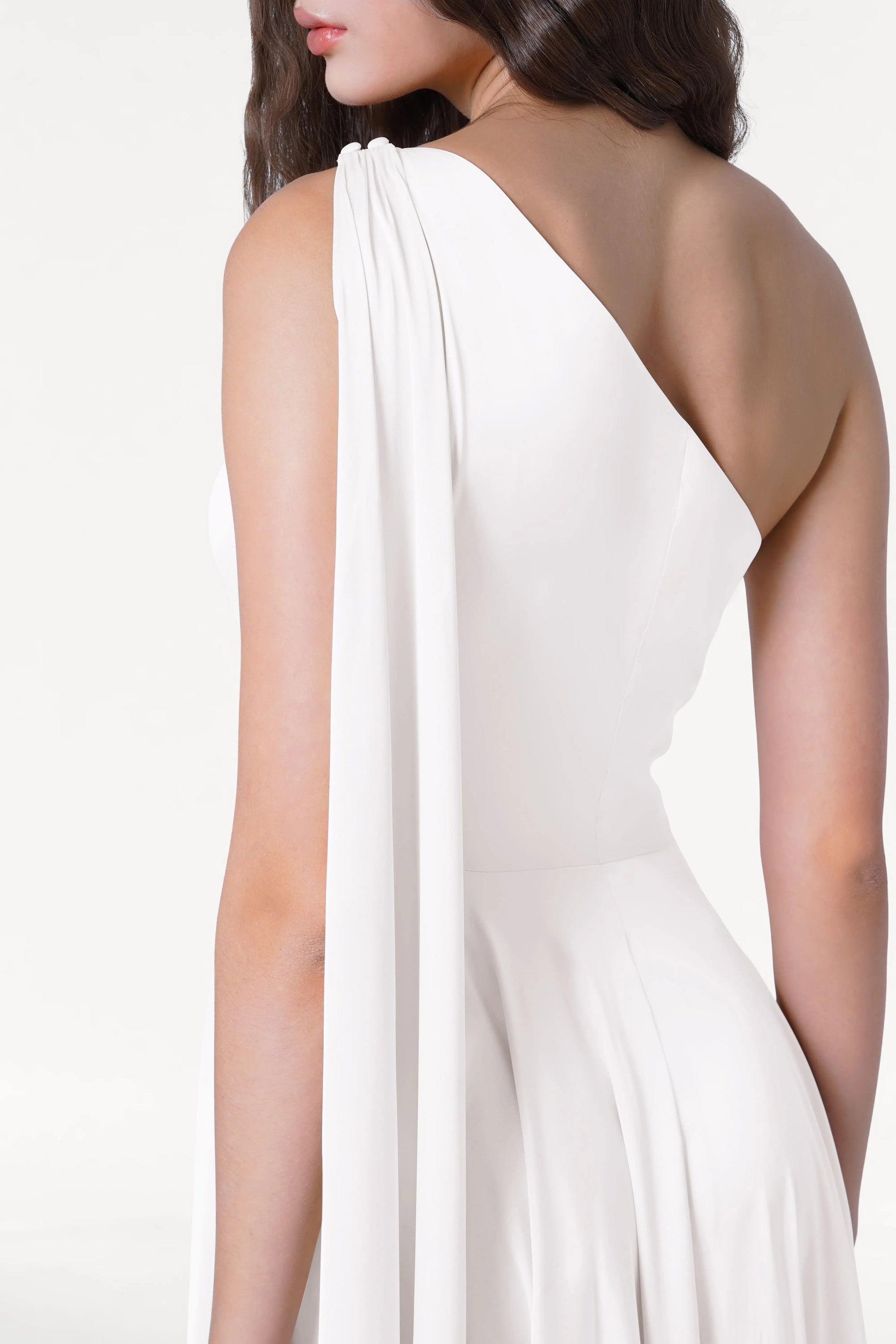 A woman models the TH&TH Lyra Dress in Ivory Satin, a sleeveless, one-shoulder, size-inclusive bridesmaid gown with draped fabric, shown from the back and side against a plain white background.