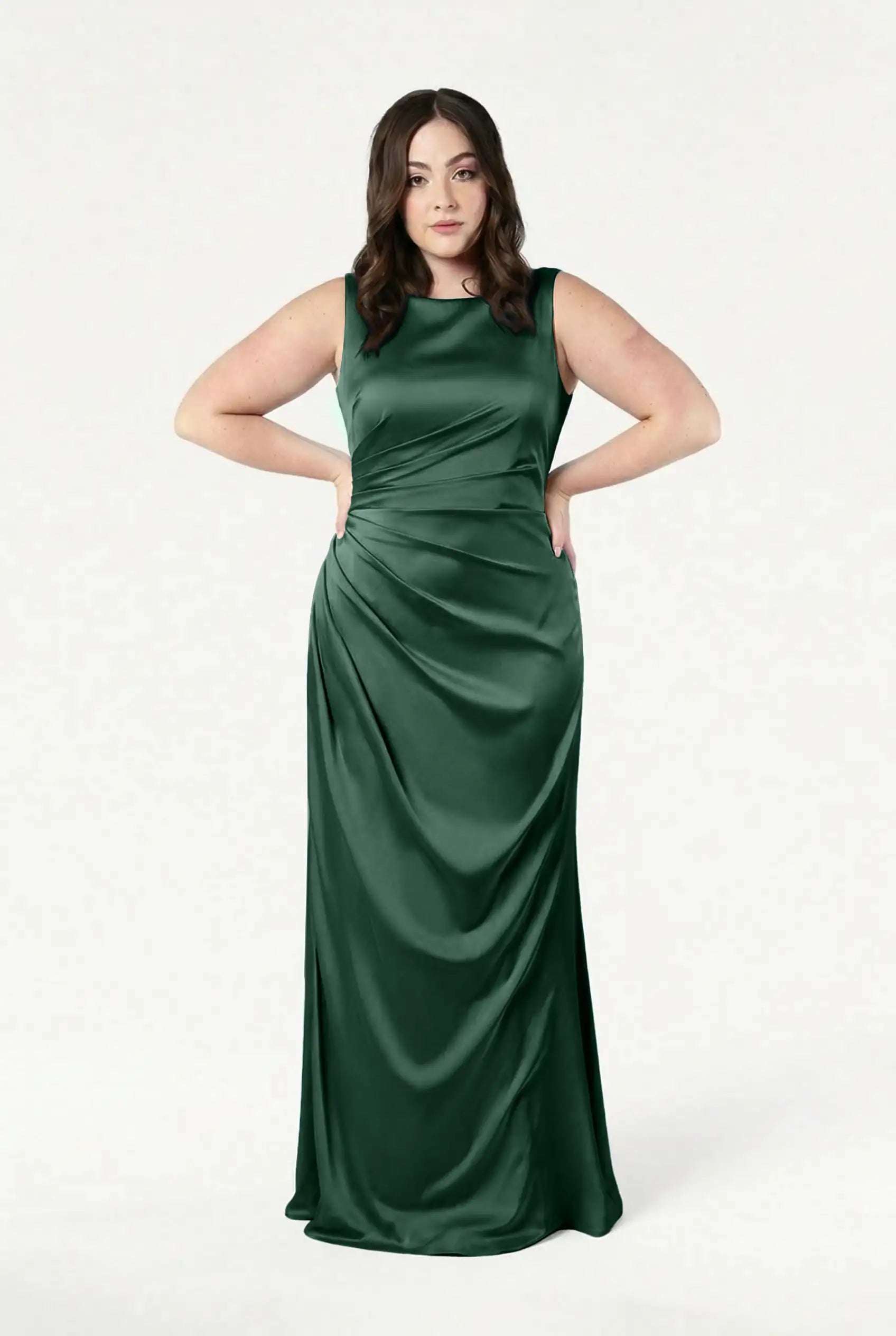 A woman poses confidently in the TH&TH Nala Bridesmaid Dress in Olive Grove Satin—a sleeveless, floor-length gown featuring subtle draping and a fitted bodice—making it a striking choice for any modern bridal party.