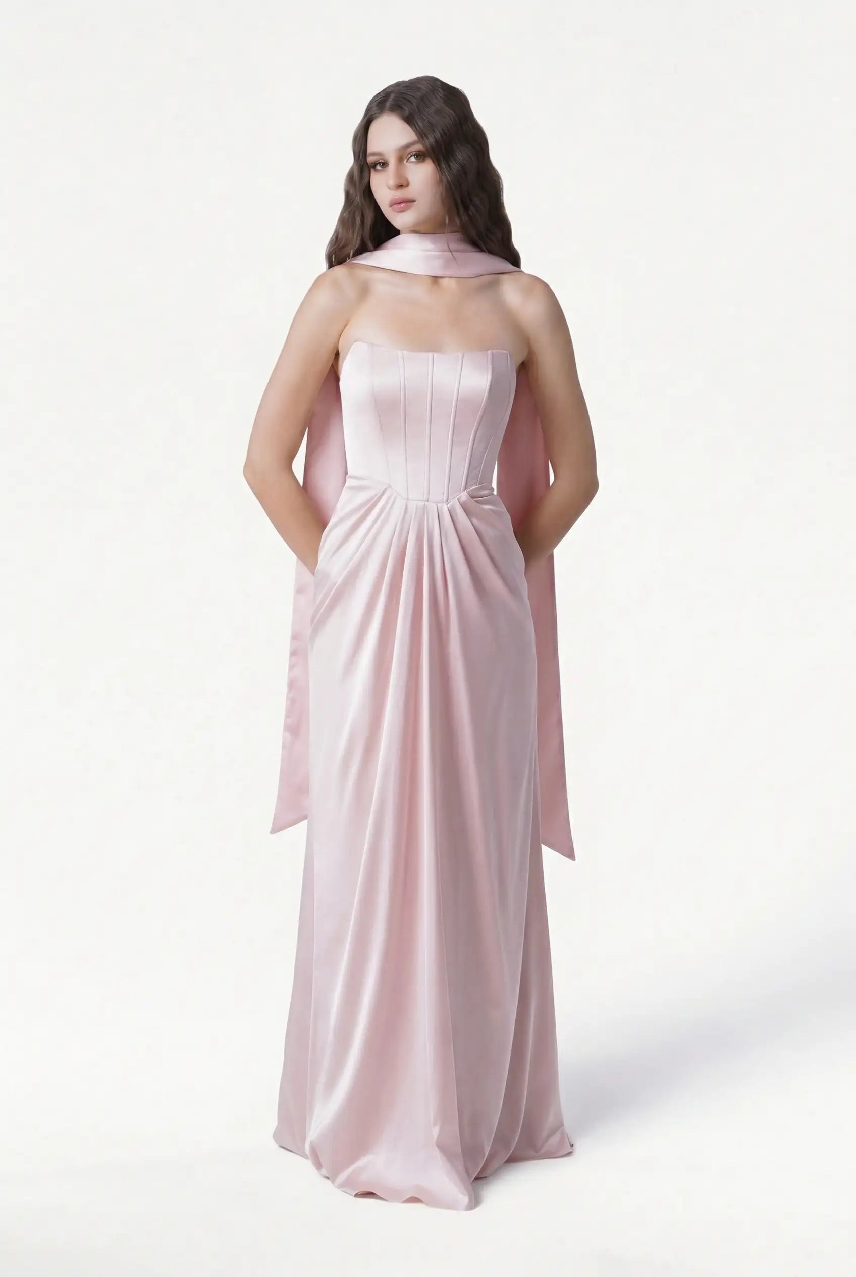 A woman with long, wavy brown hair stands against a white background in a strapless light pink satin gown, styled with the TH&TH Neck Scarf & Sash—ideal chic bridesmaid accessories.