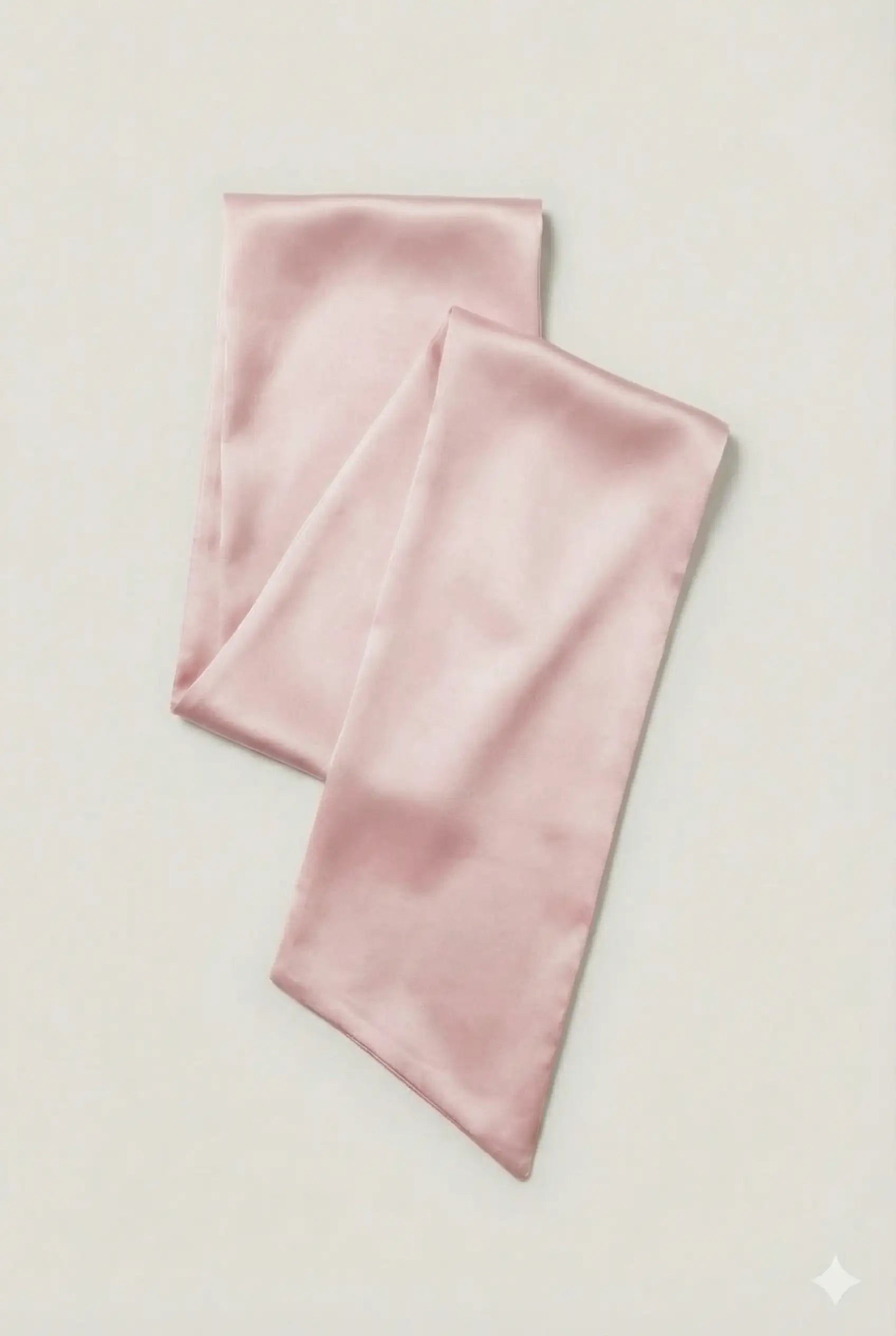 A light pink TH&TH Neck Scarf & Sash with a smooth, glossy finish is folded flat on an off-white background—ideal as a bridesmaid accessory or an elegant satin waist tie.