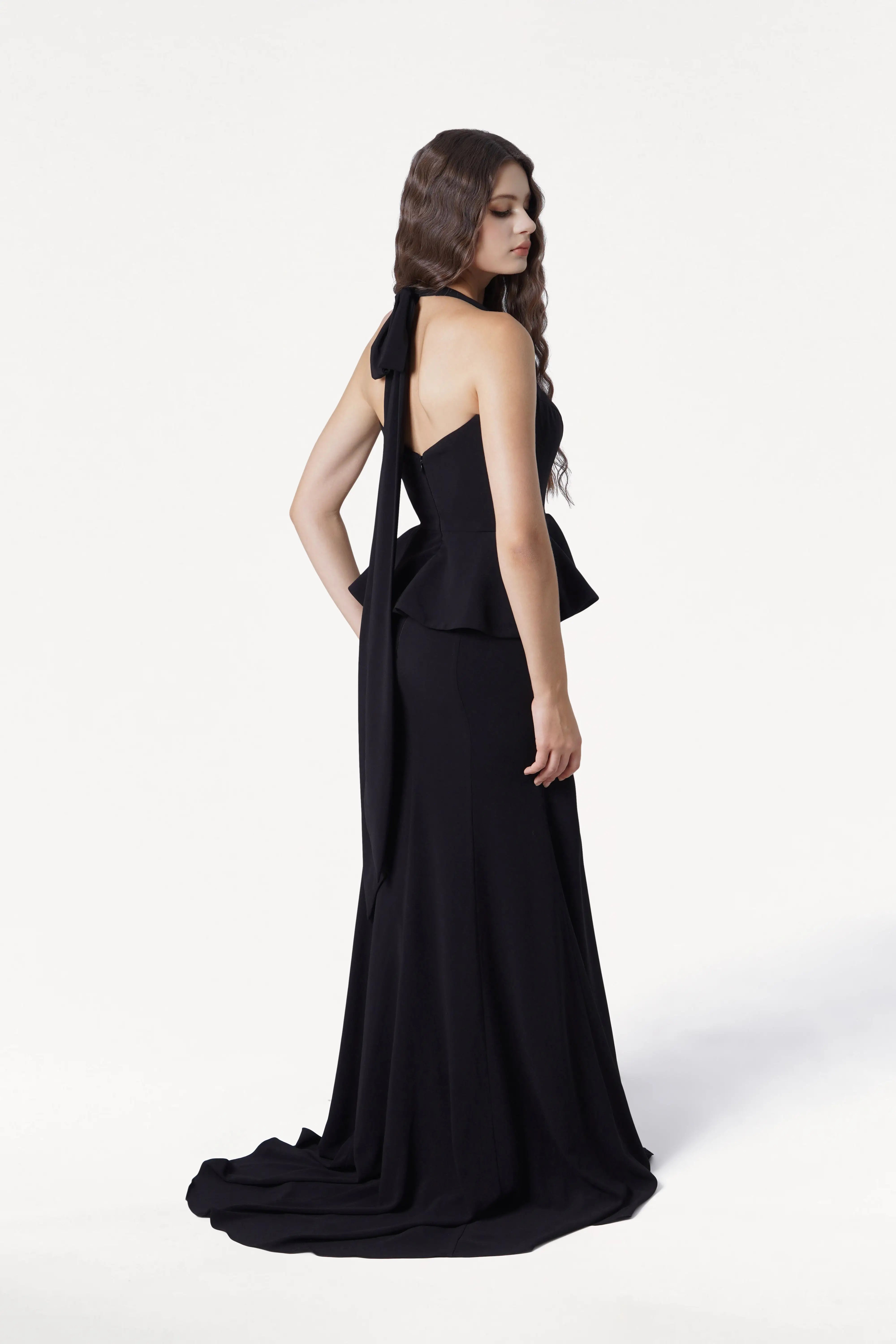 Woman wearing a black evening gown with a flowing train on a white background