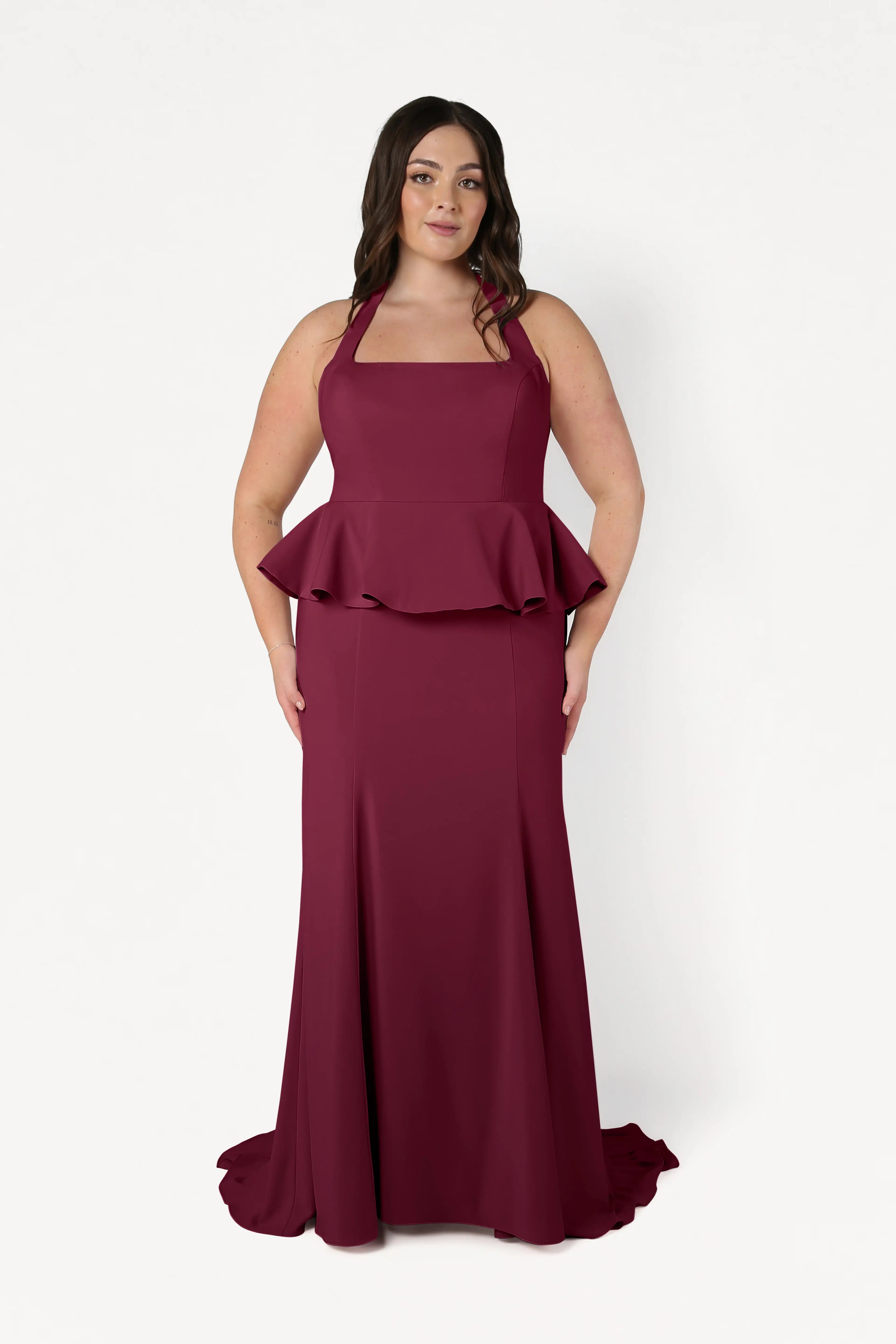 A woman with long dark hair models the TH&TH Peony Bridesmaid Dress in Merlot, featuring a sleeveless, floor-length moss crepe design with a square neckline and peplum waist, against a plain white background.