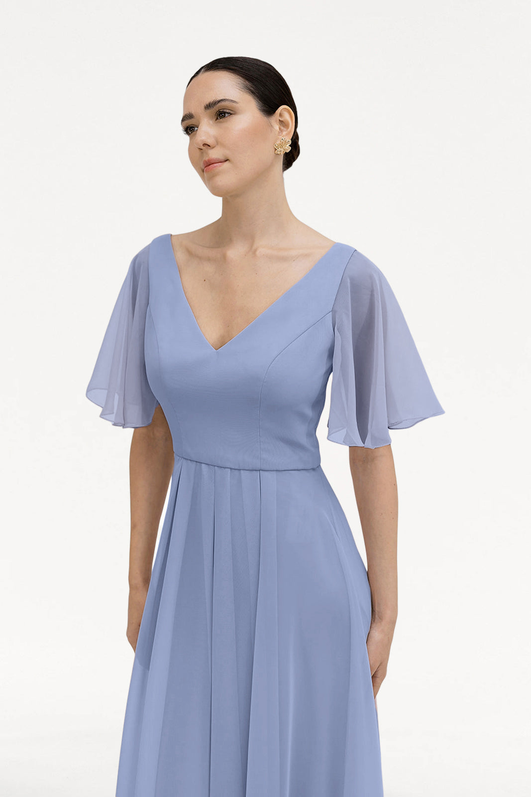 A woman models the TH&TH Phoebe Bridesmaid Dress in French Blue Chiffon, featuring short sheer flutter sleeves, standing against a white background—an elegant choice for bridesmaids.