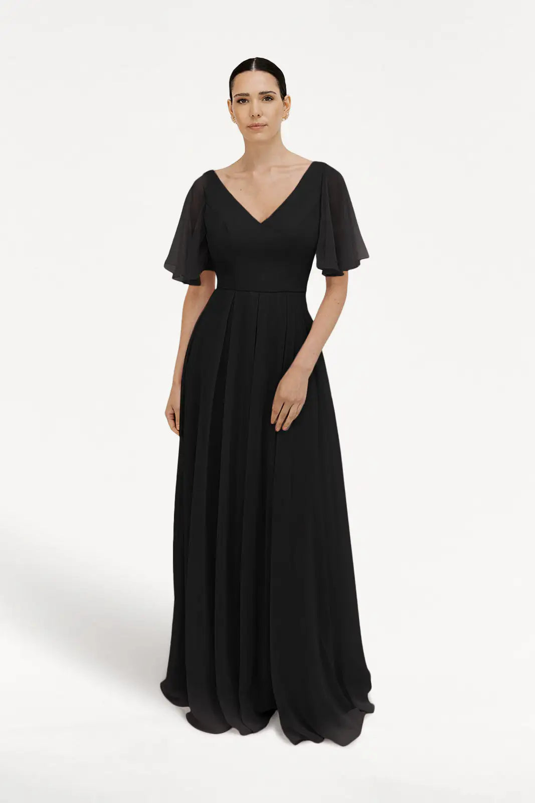 A woman with dark hair pulled back models the TH&TH Phoebe Bridesmaid Dress in Black Chiffon—a floor-length gown with flutter sleeves and a V-neck, shown against a plain white background. Perfect choice for bridesmaids.