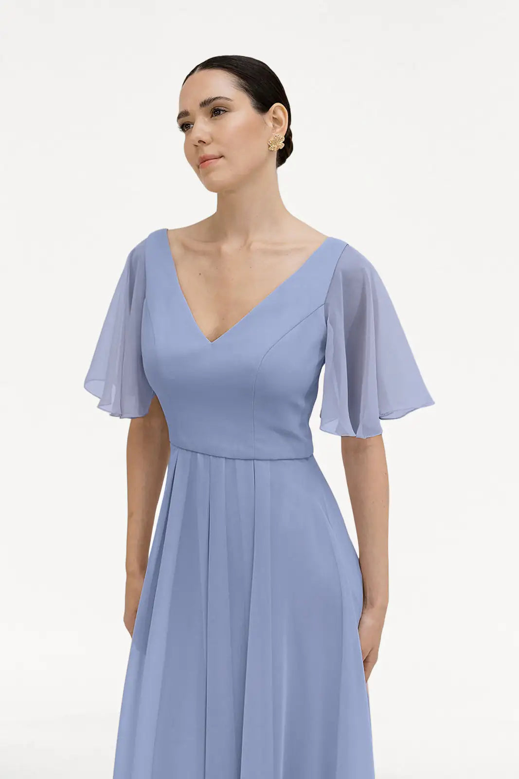 A woman models the TH&TH Phoebe Bridesmaid Dress in French Blue Chiffon, featuring short sheer flutter sleeves, standing against a white background—an elegant choice for bridesmaids.