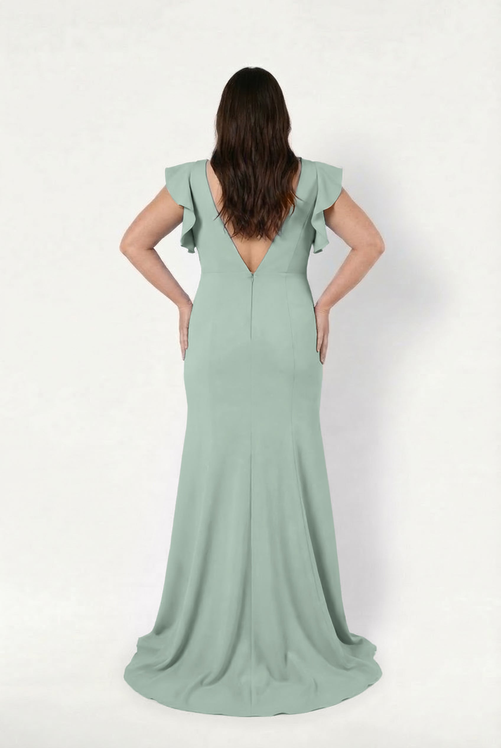 A woman with long brown hair faces away, modeling the TH&TH Cecelia Moss Crepe Bridesmaid Dress in Sage Green. The floor-length gown features ruffled sleeves and a V-back, shown against a plain white background.