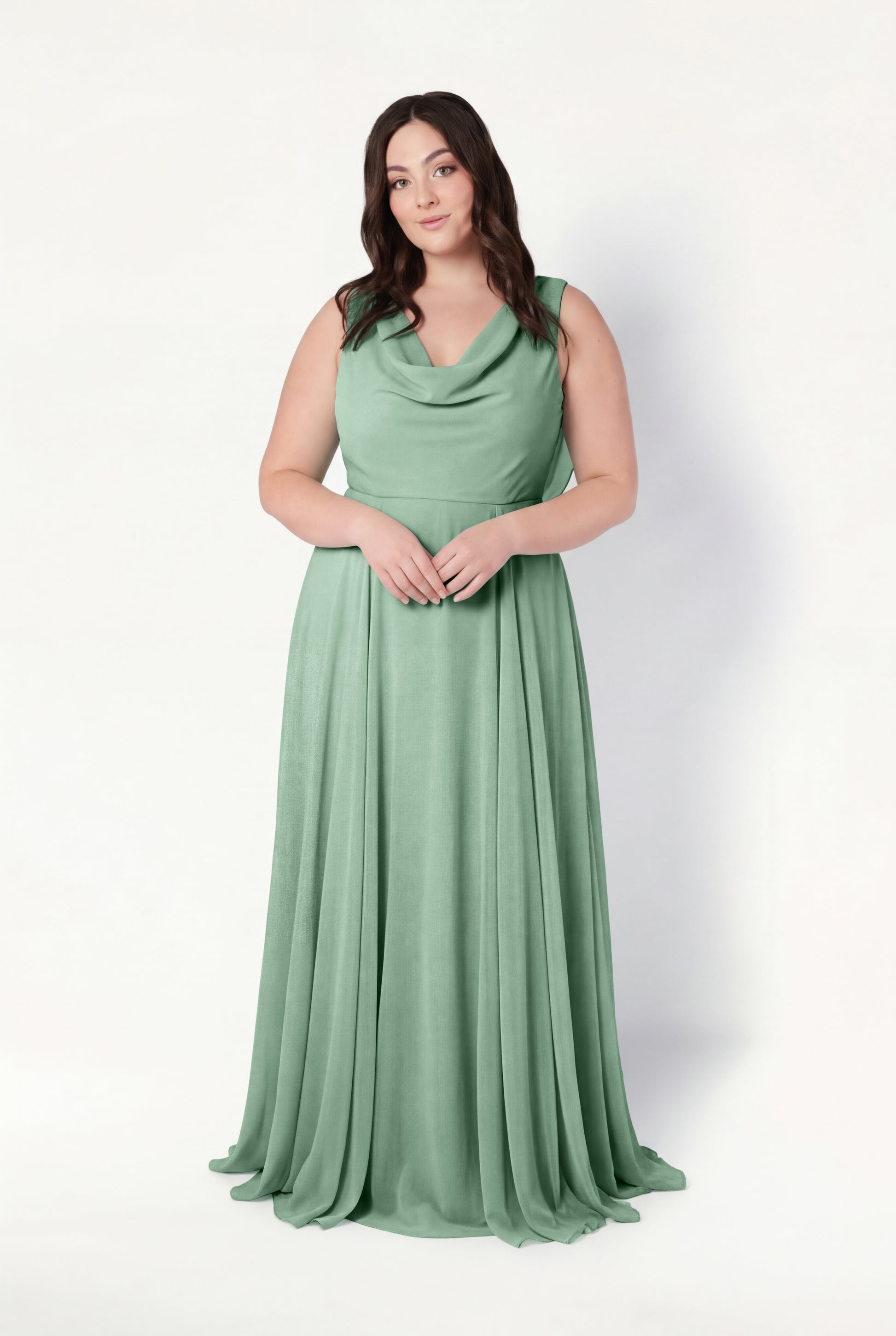 A woman with long brown hair models the TH&TH Athena Bridesmaid Dress in sage green chiffon, a sleeveless, floor-length gown with a draped cowl neck, standing against a plain white background.