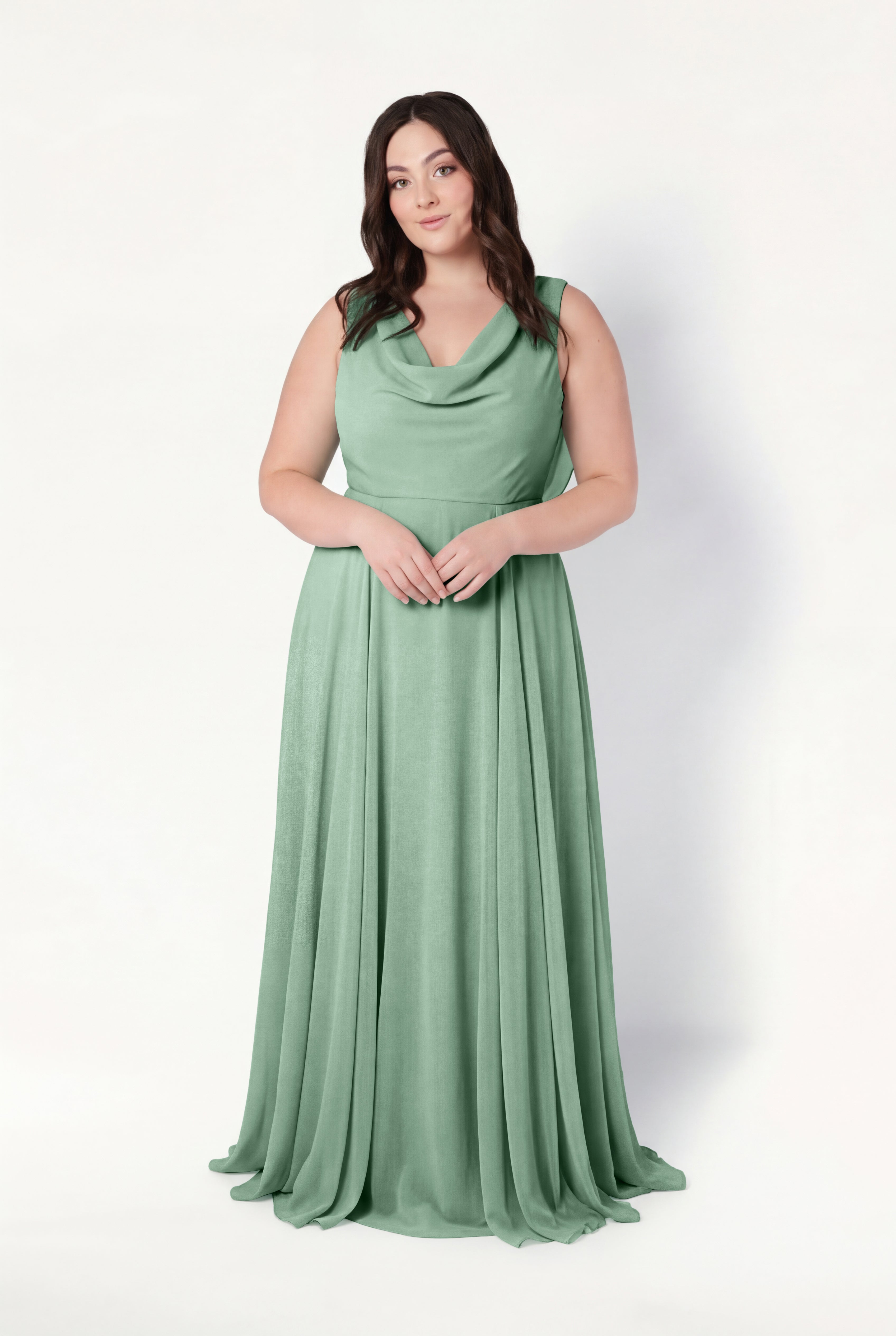 A woman with long brown hair models the TH&TH Athena Bridesmaid Dress in sage green chiffon, a sleeveless, floor-length gown with a draped cowl neck, standing against a plain white background.