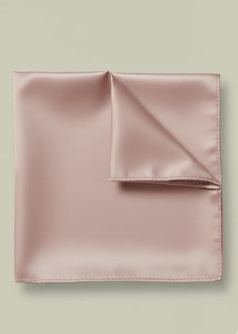 A neatly folded light pink TH&TH Satin Pocket Square is displayed against a plain beige background.