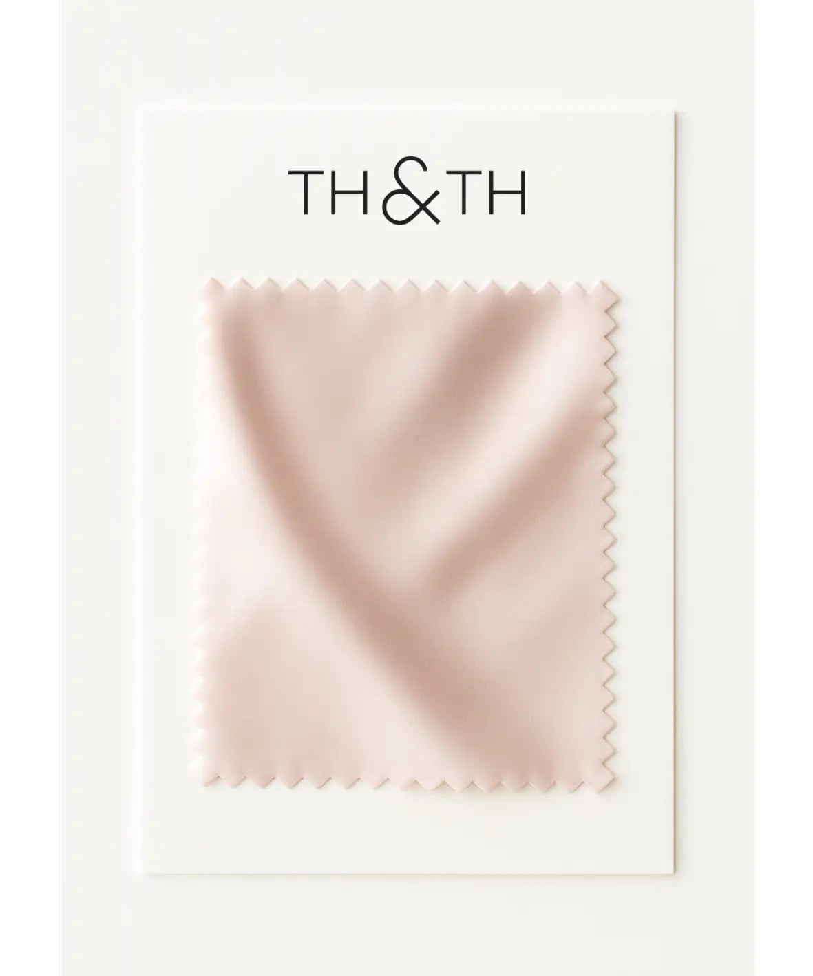 A rectangular Satin Swatch by TH & TH with soft blush pink satin and zigzag edges, featuring the brand at the top, is set against a white background—ideal inspiration for a bridesmaid look.